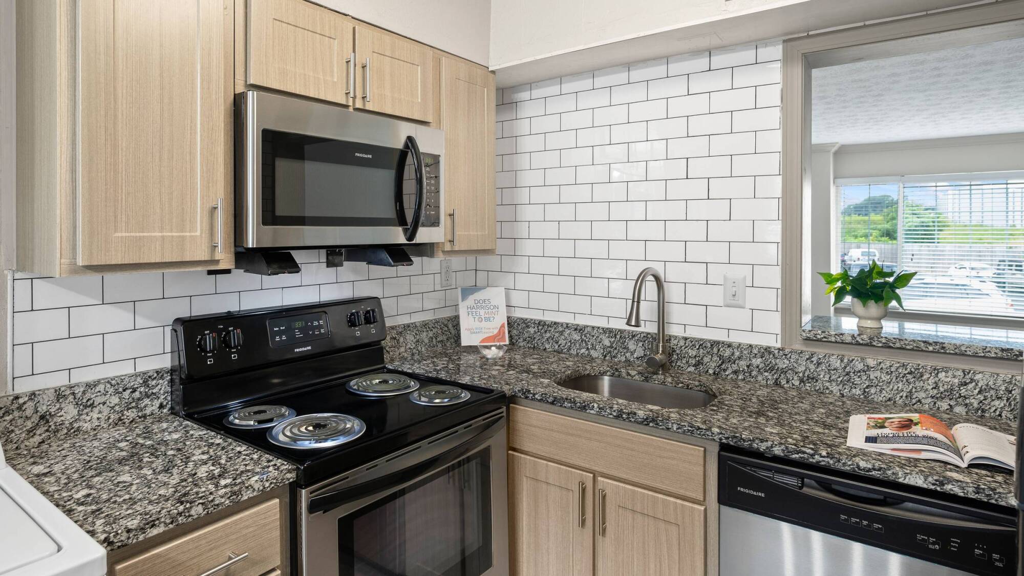 Modern kitchen with stainless steel appliances, granite countertops, and white subway tile backsplash.