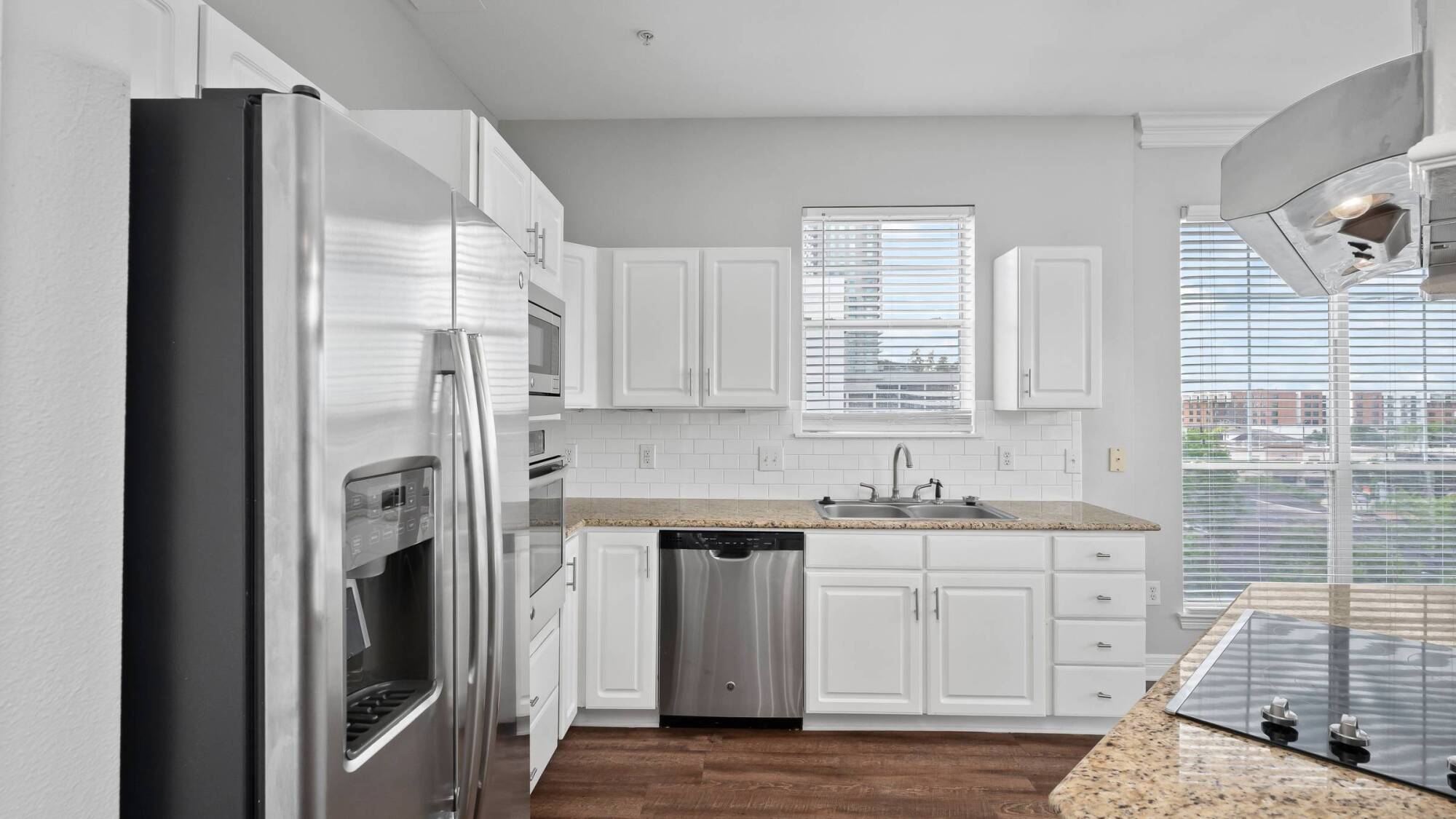 Modern kitchen with white cabinets, stainless steel appliances, granite countertops, and a window above the sink.