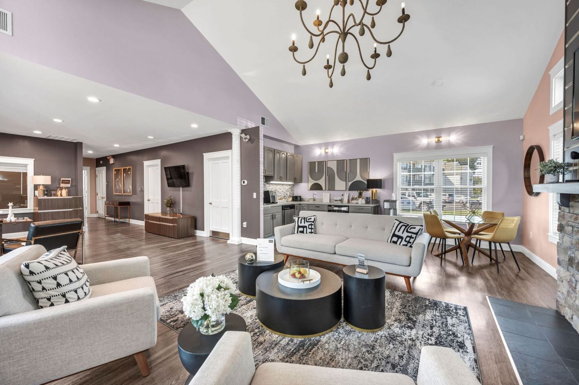 Modern open-concept living room and kitchen with stylish furniture, hardwood floors, and large windows.