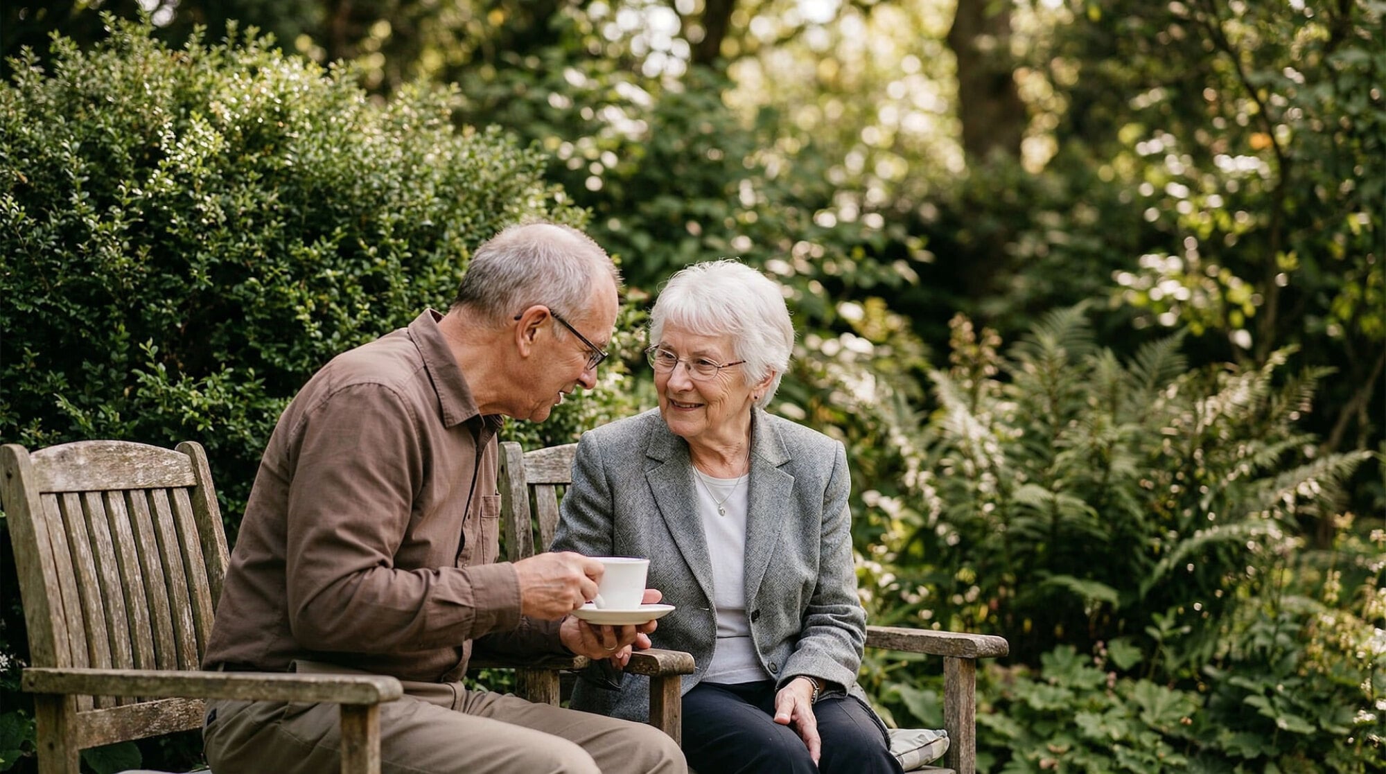 Two friends sharing coffee on a garden bench, illustrating relaxed outdoor living near The Landings at Sea Forest in New Port Richey, FL.