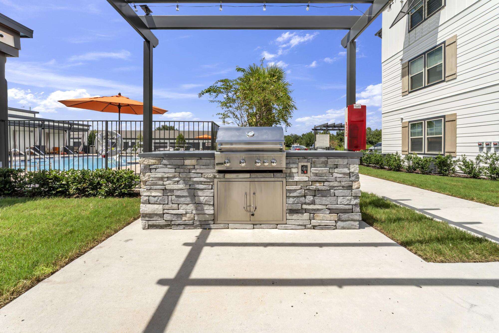 Outdoor grilling station at Pointe Grande Plant City featuring stainless steel BBQs under a modern pergola.
