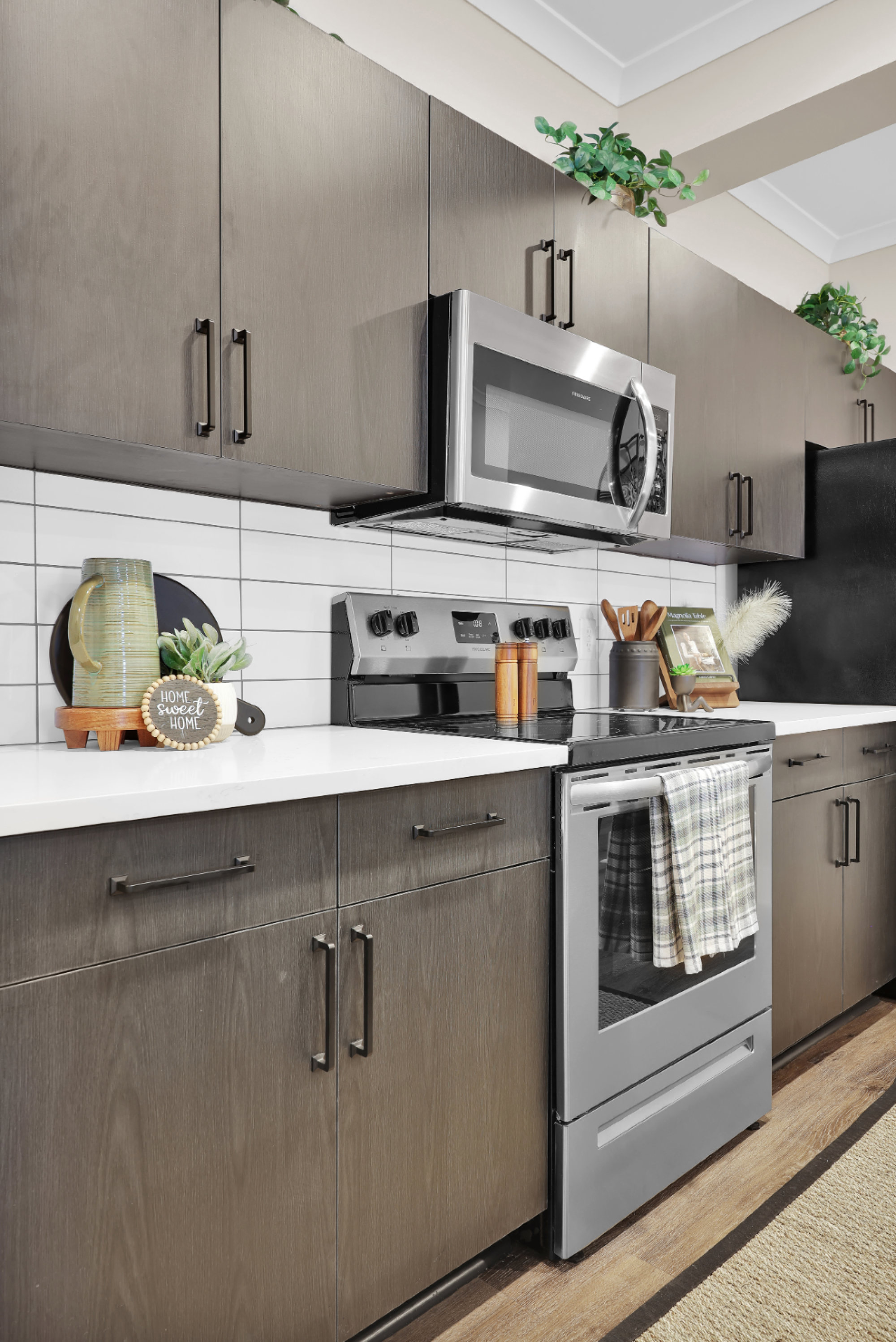 Apartment kitchen with dark cabinetry, white subway tile backsplash, and stainless steel appliances at Pointe Grand Jacksonville West in Jacksonville, Florida.