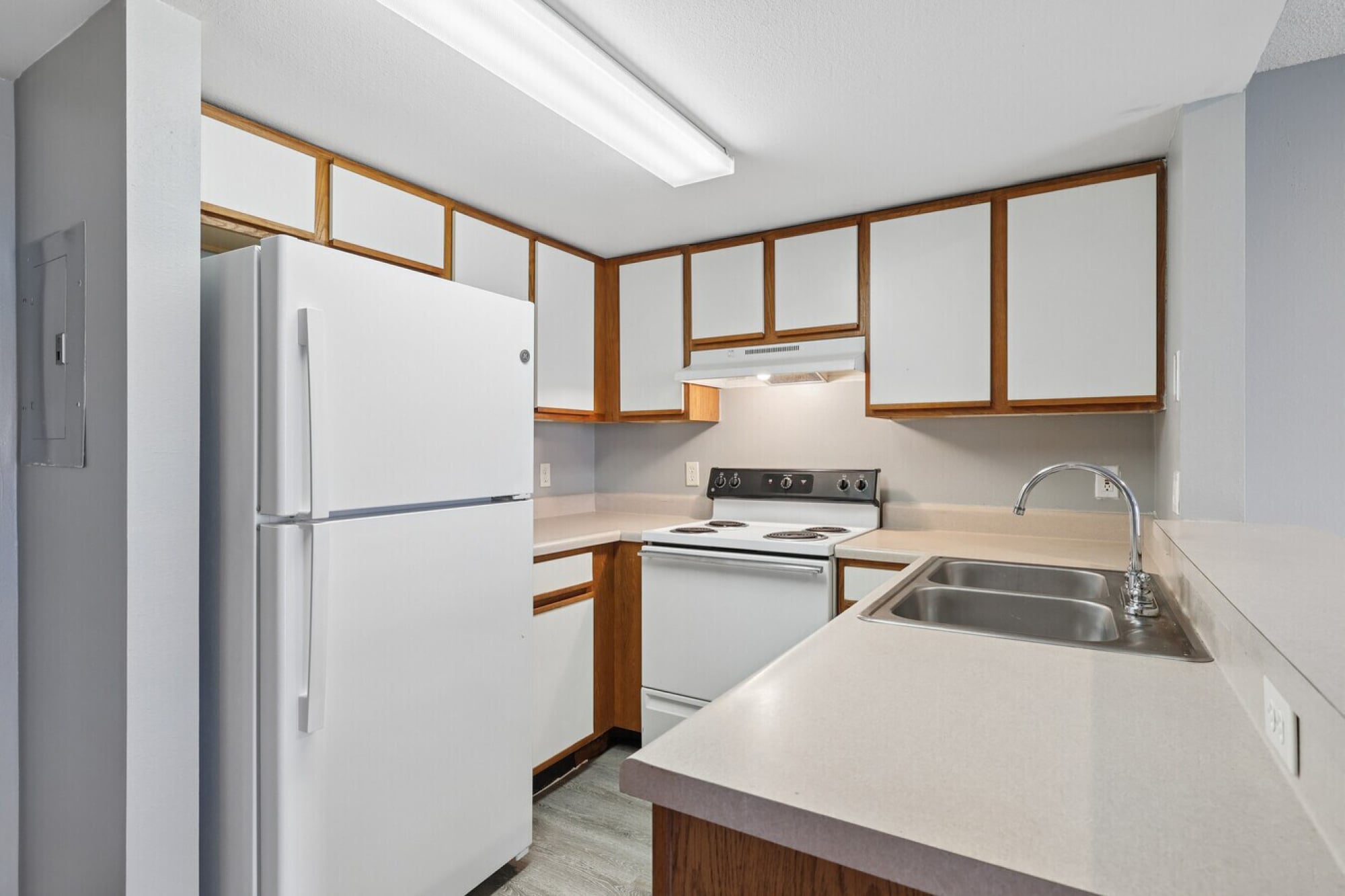 The Landings at Sea Forest apartment kitchen in New Port Richey, FL with a refrigerator, electric range, double sink, and plenty of cabinet space.