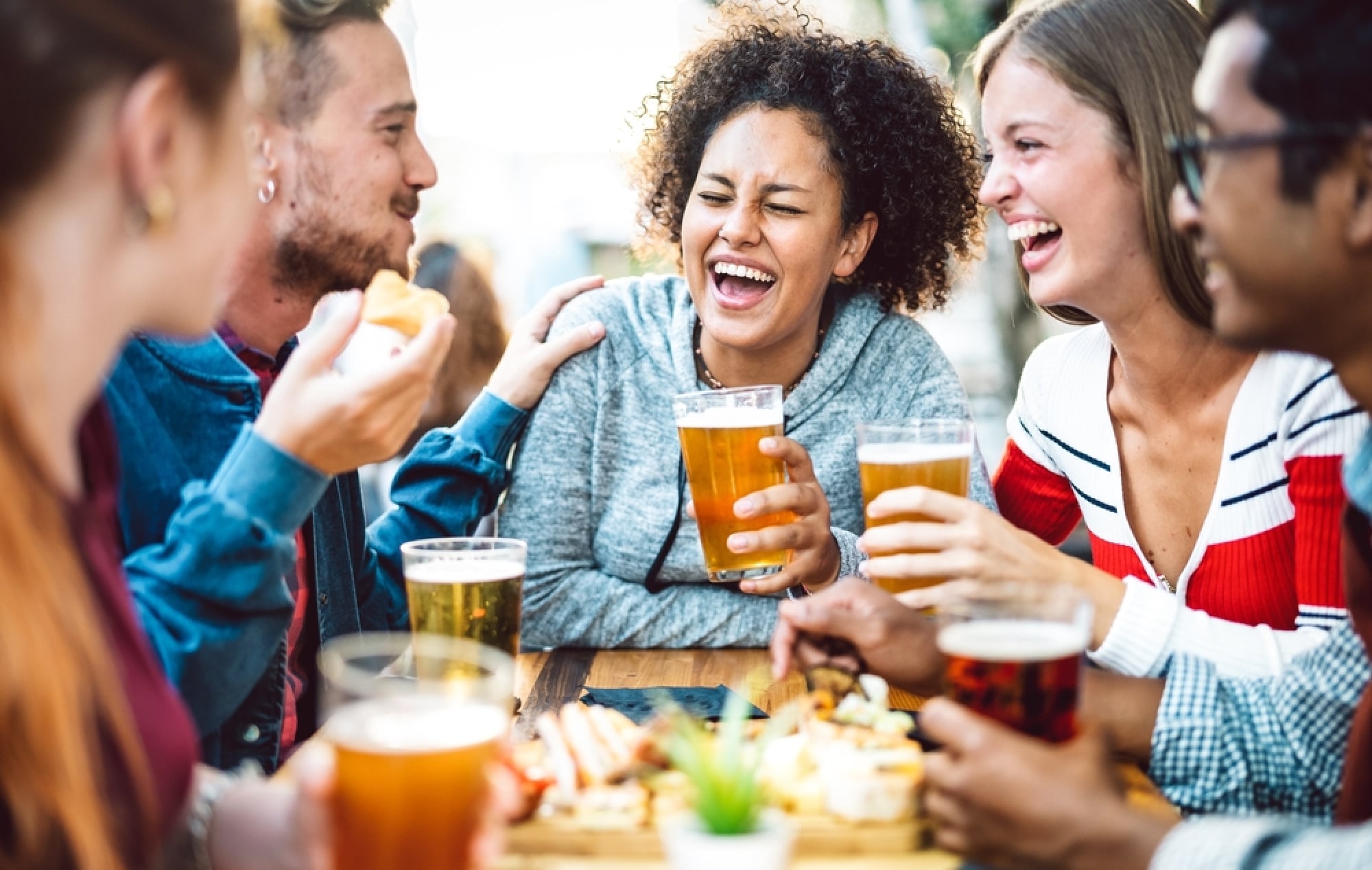 Friends drinking beer around table, laughing