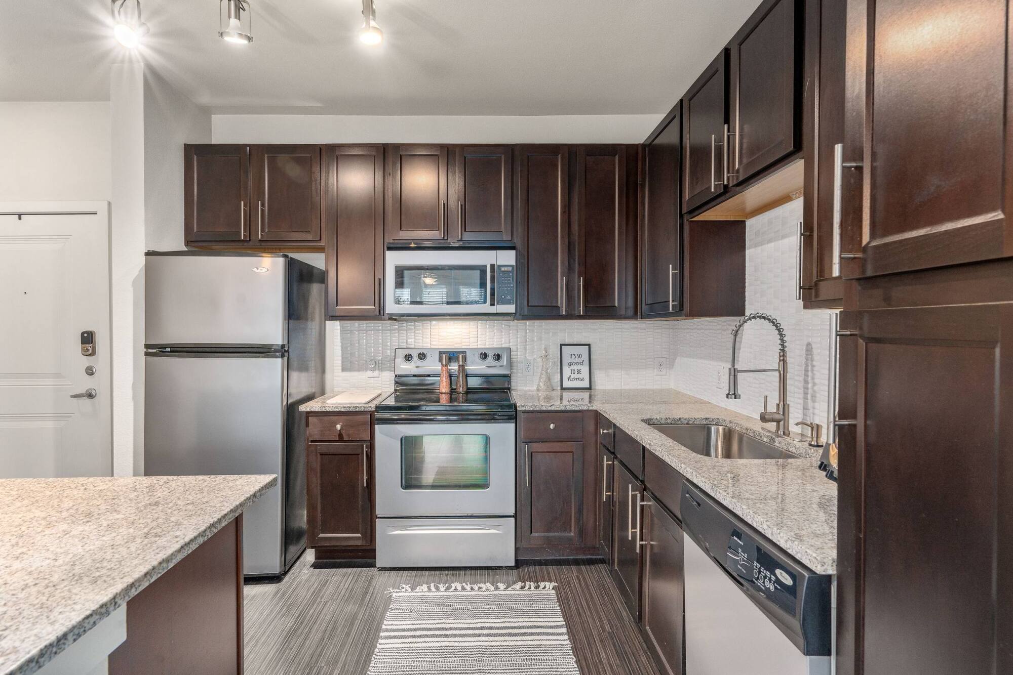 Modern kitchen with dark wood cabinets, stainless steel appliances, and granite countertops.