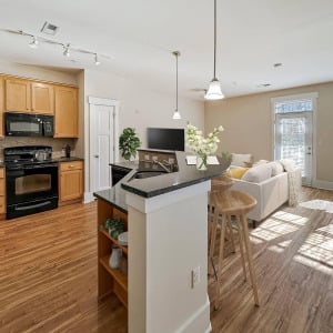 Townhomes at Chapel Watch Village townhome kitchen with floor-to-ceiling cabinetry, faux wood flooring, and an island counter and bar