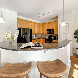 Townhomes at Chapel Watch Village townhome kitchen with floor-to-ceiling cabinetry, faux wood flooring, and an island counter and bar with bar stools