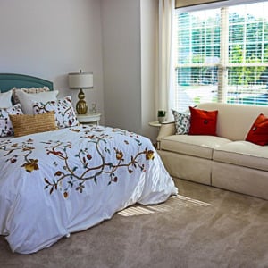 Townhomes at Chapel Watch Village townhome bedroom with a large bed, large window, carpet, and a love seat