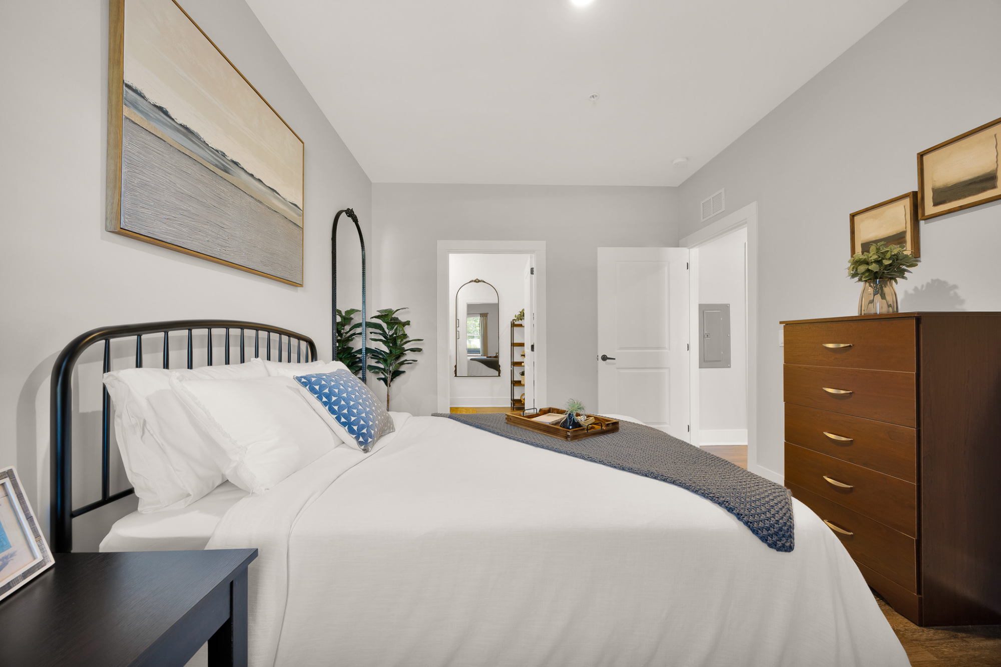 Bright bedroom with a large bed, white linens, and neutral decor.