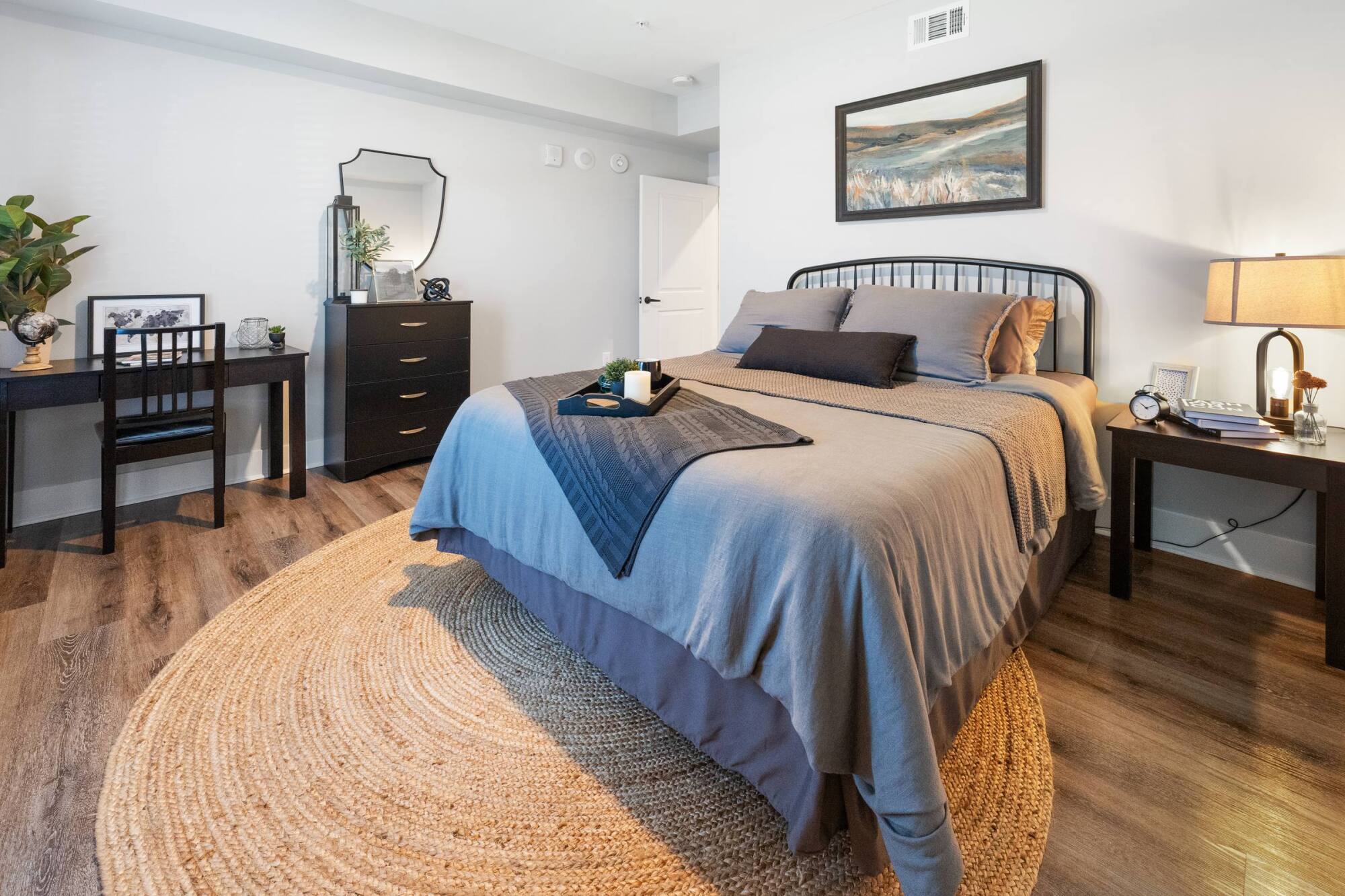 Bedroom with blue bedding, woven rug, and wood floors