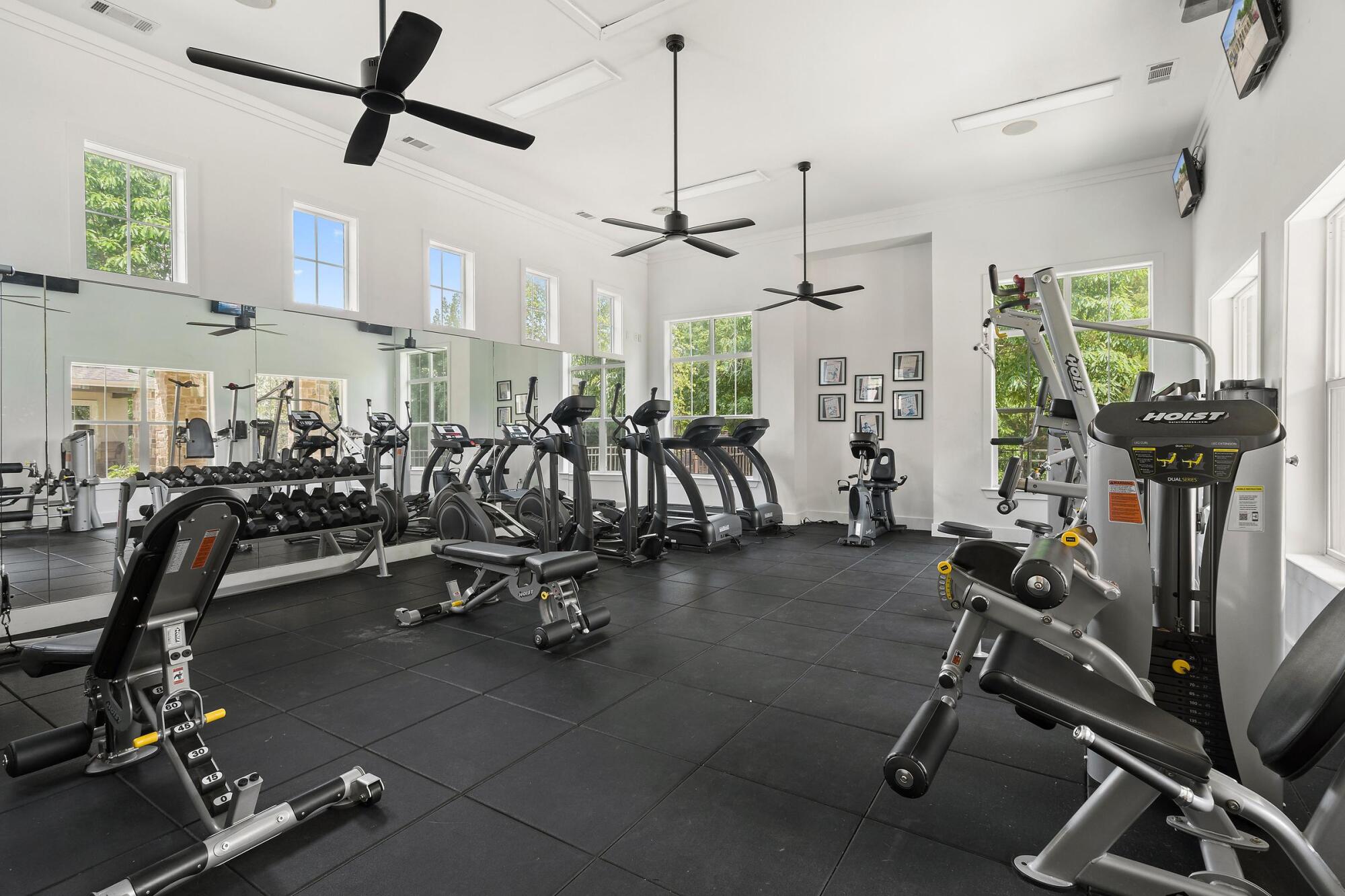Fitness center at Bella Ruscello in Duncanville, TX featuring cardio machines, weight stations, mirrors, and natural light