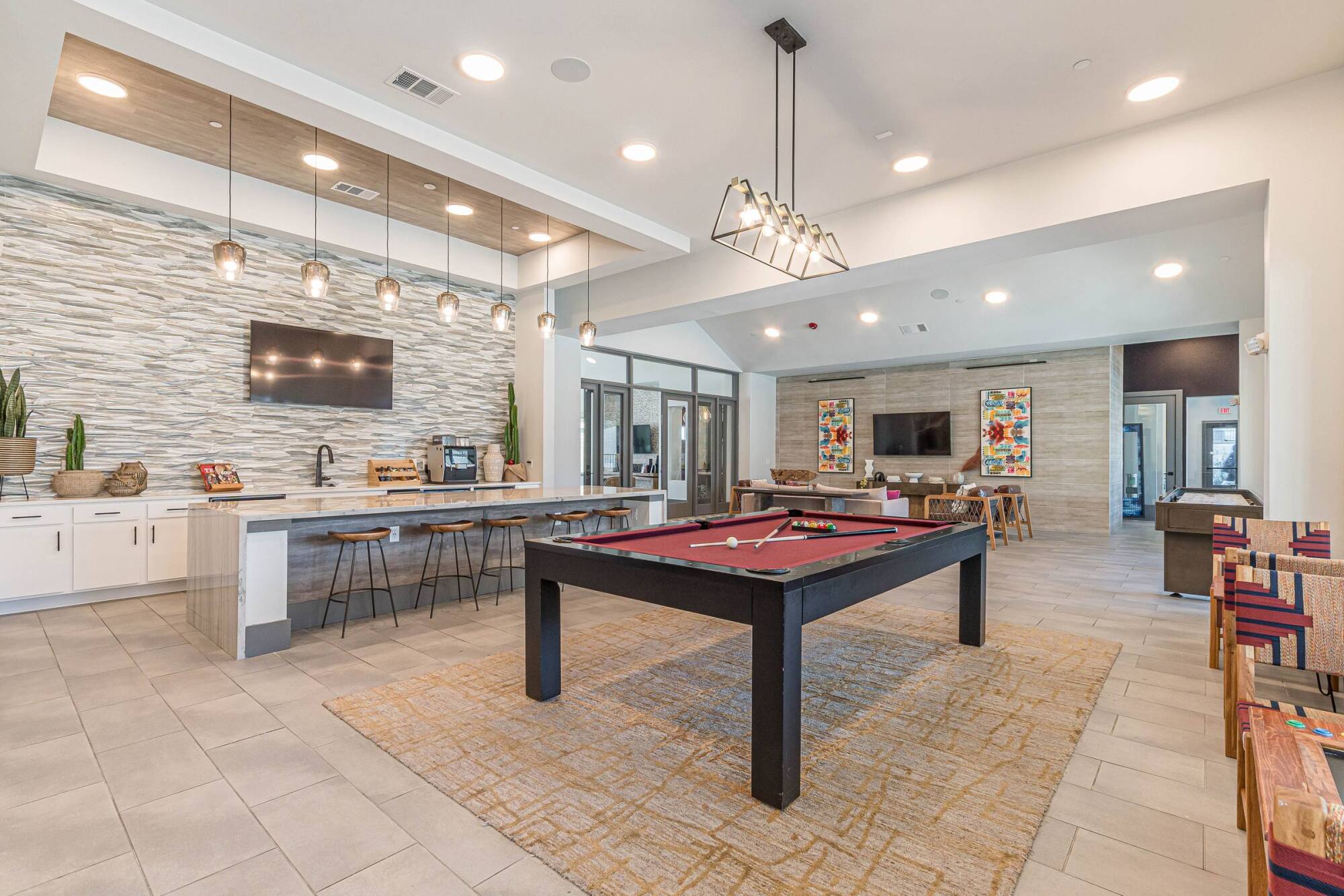 Modern lounge with a pool table, bar seating, wall art, and a TV, featuring bright and inviting decor.