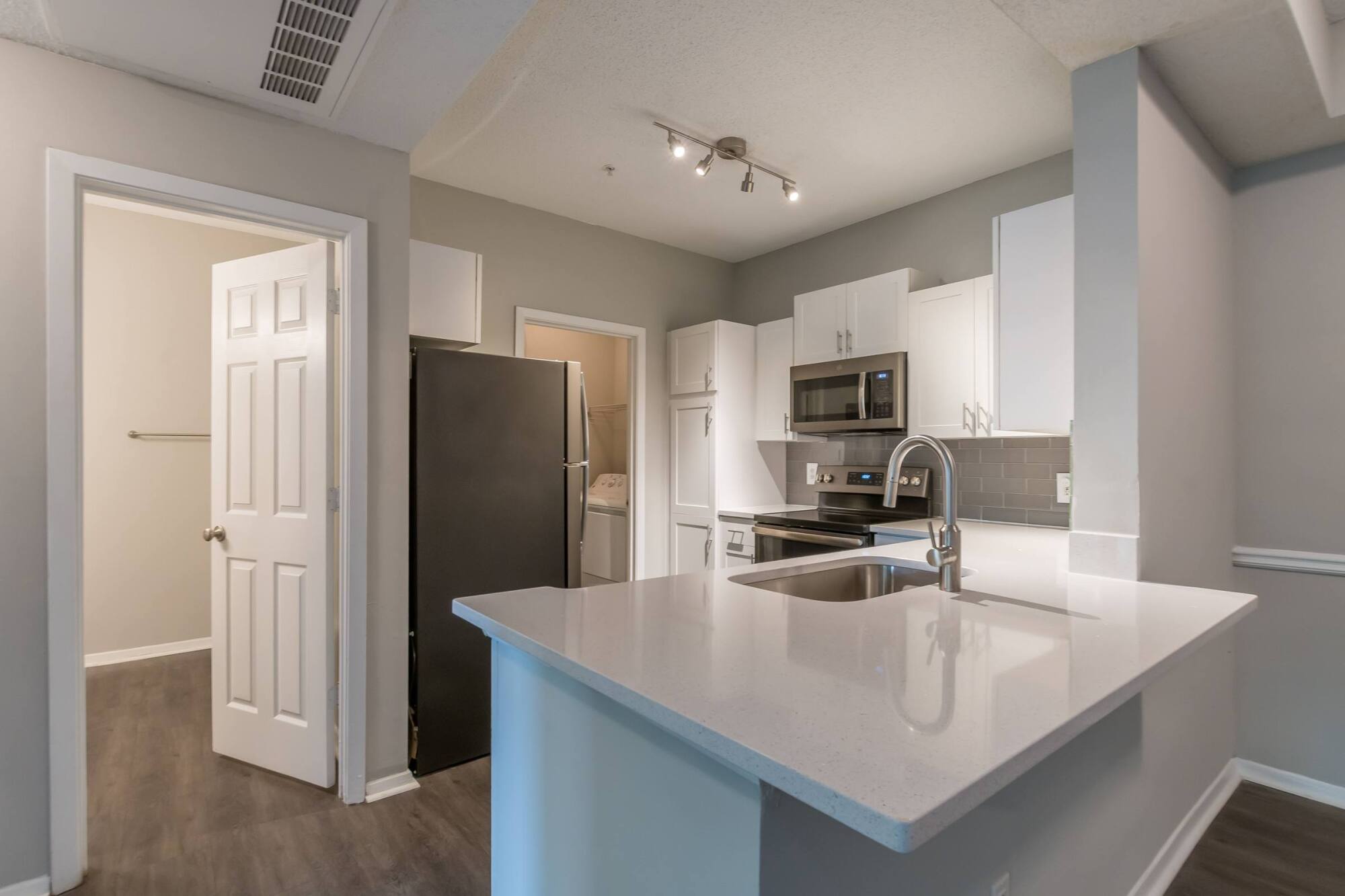 Modern kitchen with white cabinets, stainless steel appliances, and an island with a sink and faucet.