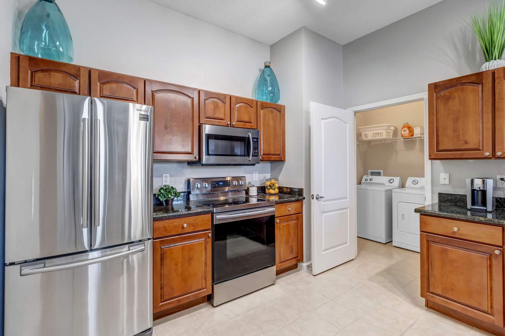Modern kitchen with wooden cabinets, stainless steel appliances, and adjacent laundry room with washer and dryer.