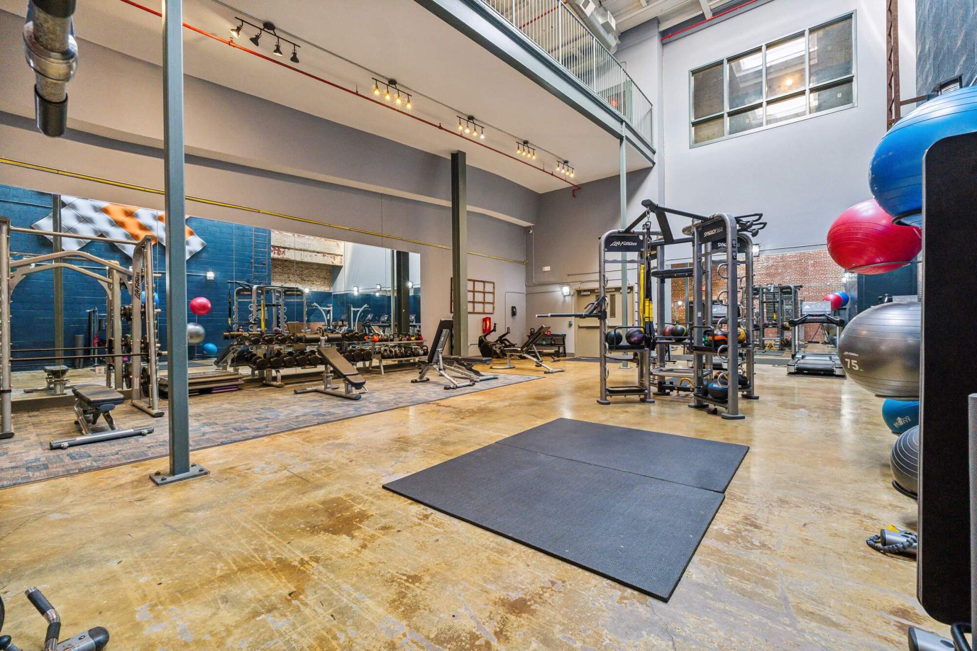 Spacious gym with weight machines, benches, free weights, and large mirrors on the walls.