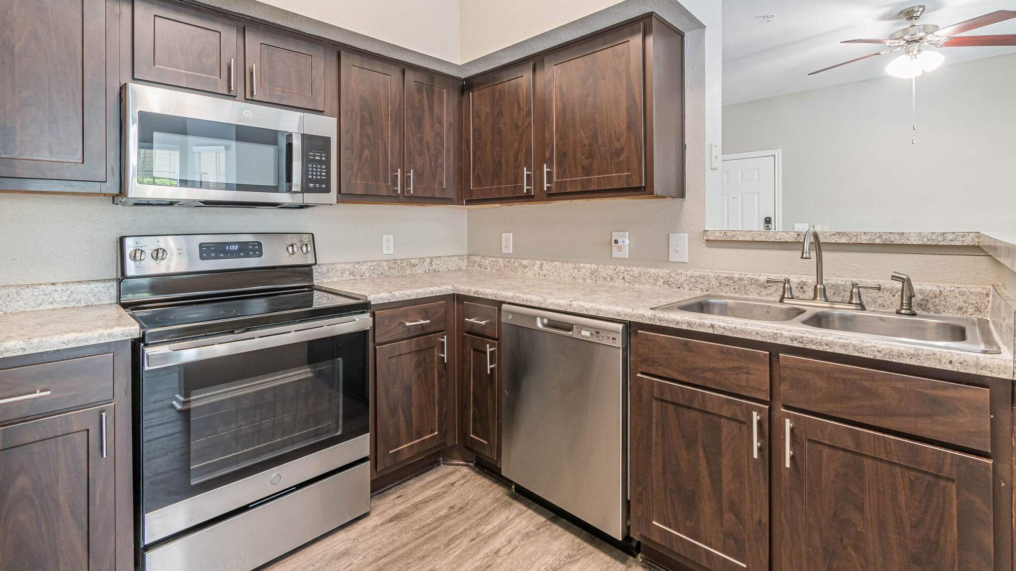 Modern kitchen with dark wood cabinets, stainless steel appliances, and granite countertops.
