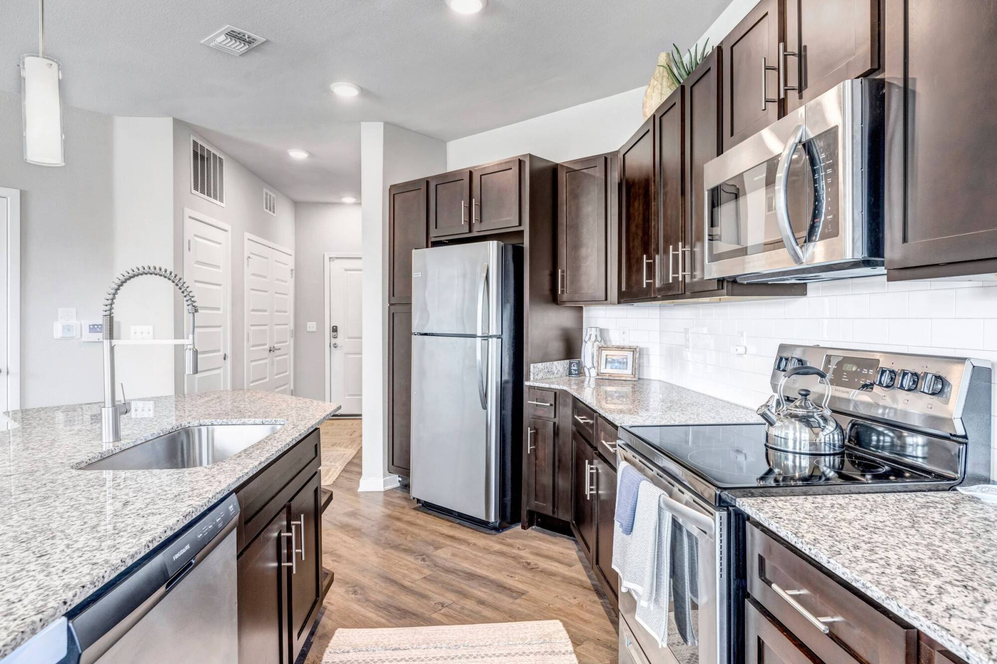Modern kitchen with stainless steel appliances, dark wood cabinets, and granite countertops.