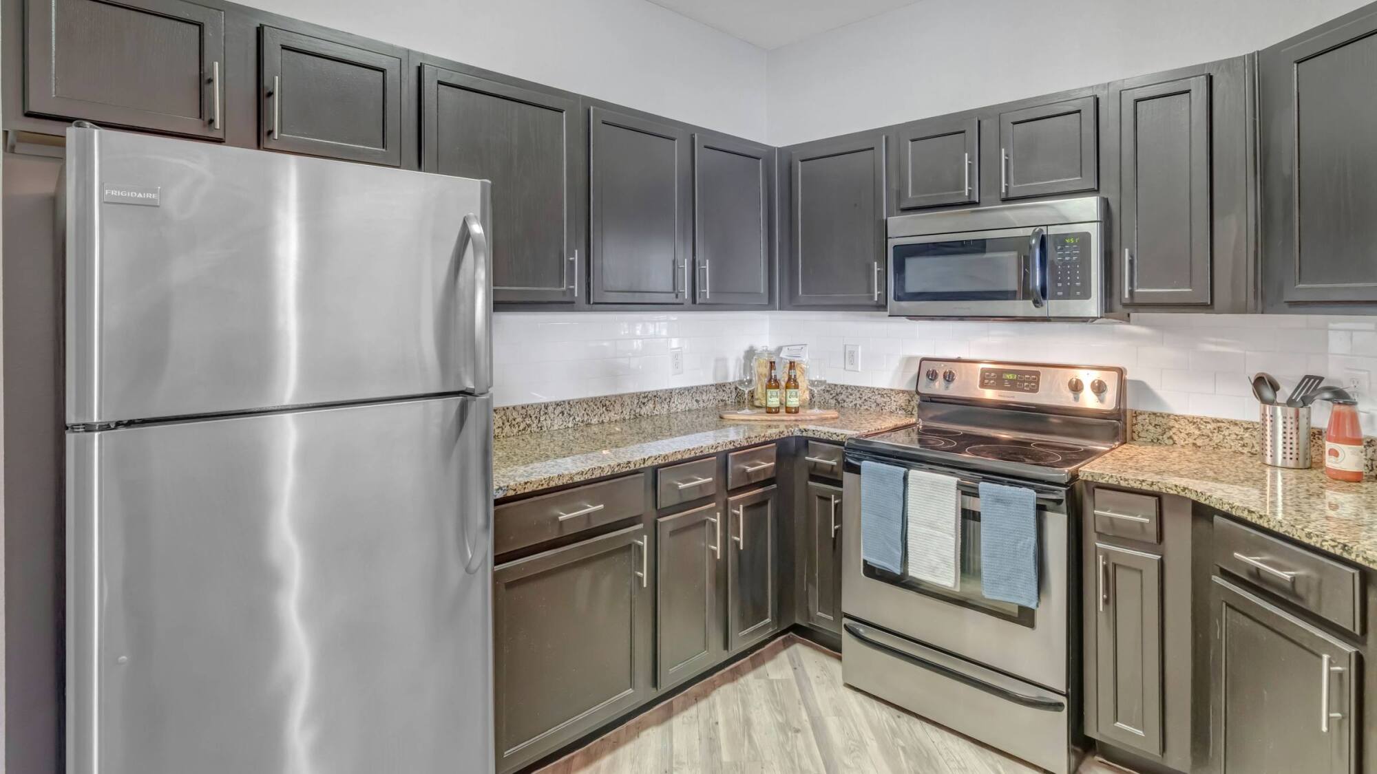 Modern kitchen with dark cabinets, stainless steel appliances, and granite countertops.