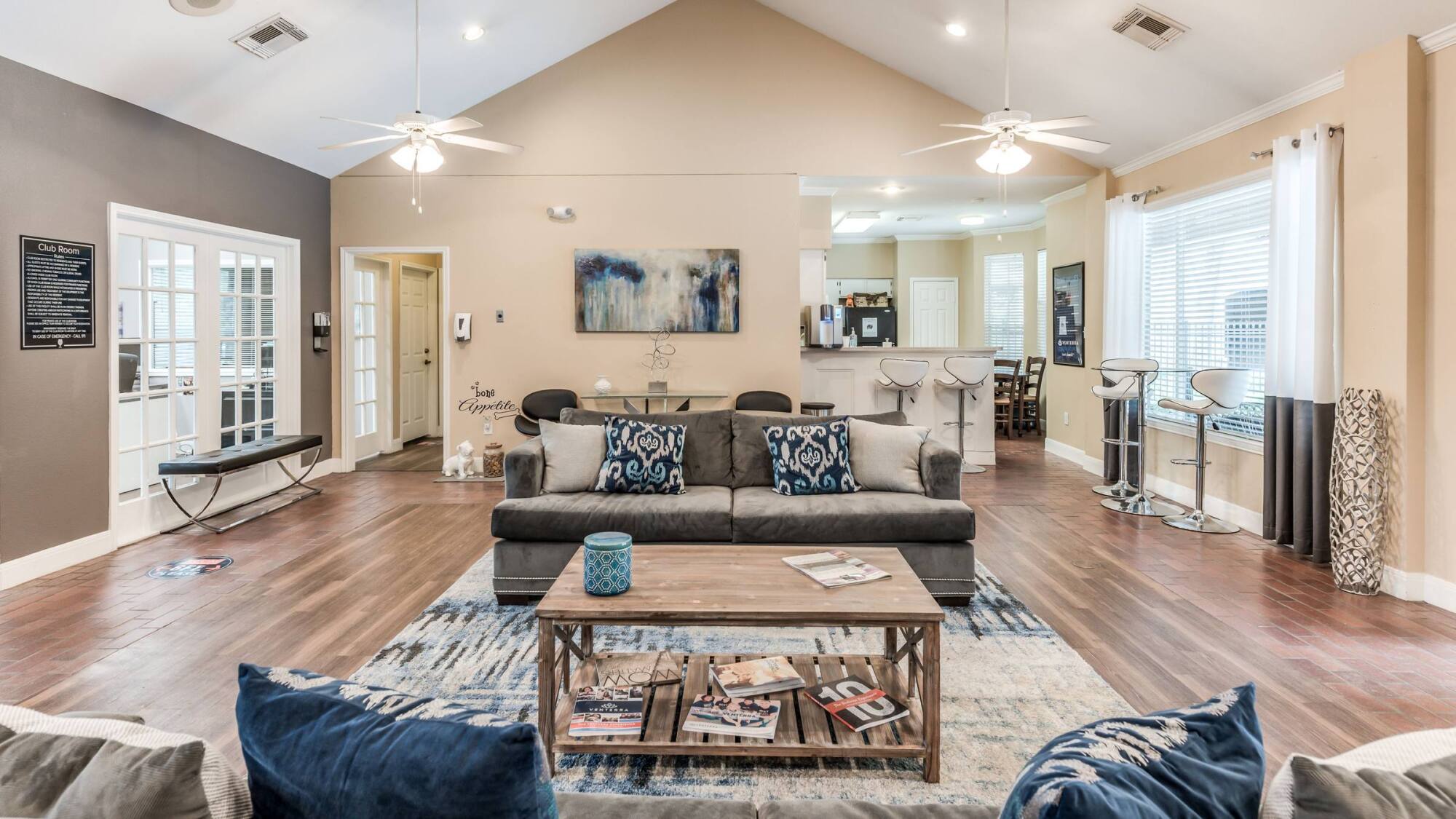 Resident clubroom at Forest View in The Woodlands, TX with vaulted ceilings, a sectional sofa, artwork, and barstool seating.