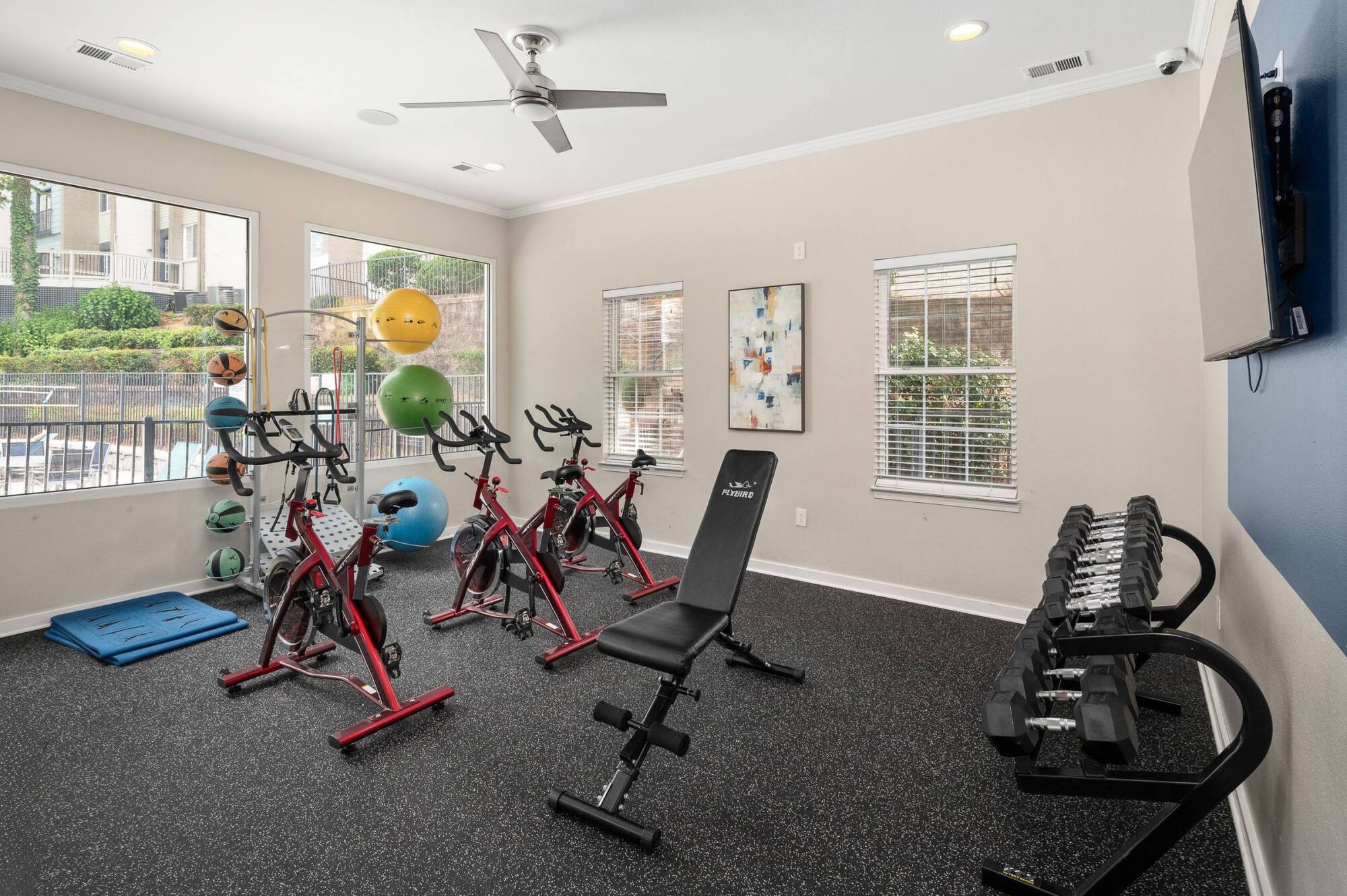 Fitness center at The Whitney with spin bikes, free weights, an adjustable bench, and a rack of medicine balls.