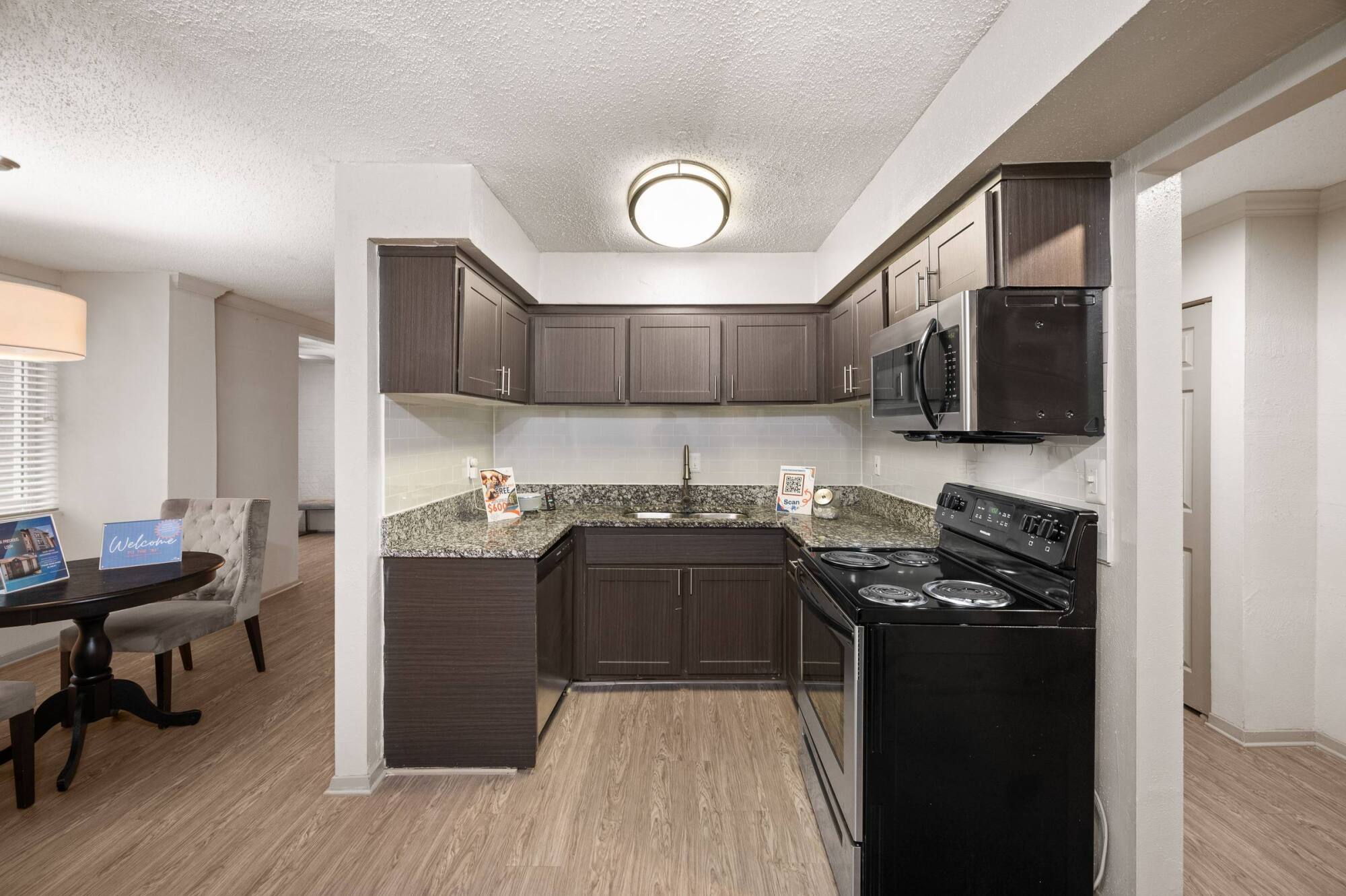 Kitchen at The Whitney with espresso shaker cabinets, granite countertops, a black electric range, and a stainless microwave.
