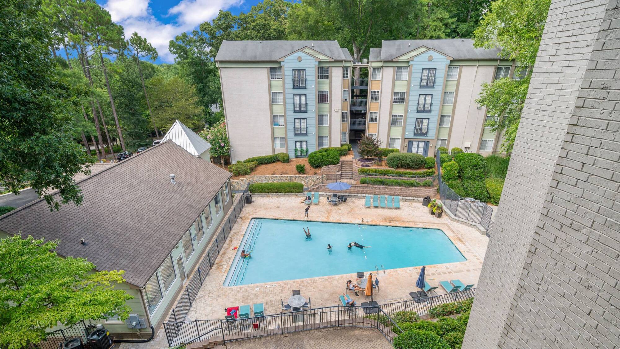 Aerial view of the pool and courtyard at The Whitney in Atlanta, GA, framed by four-story apartment buildings and mature trees.