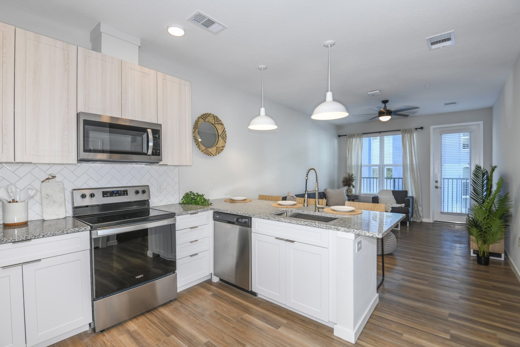 Open-concept apartment kitchen with granite peninsula, stainless appliances, and living room view at The Griffin