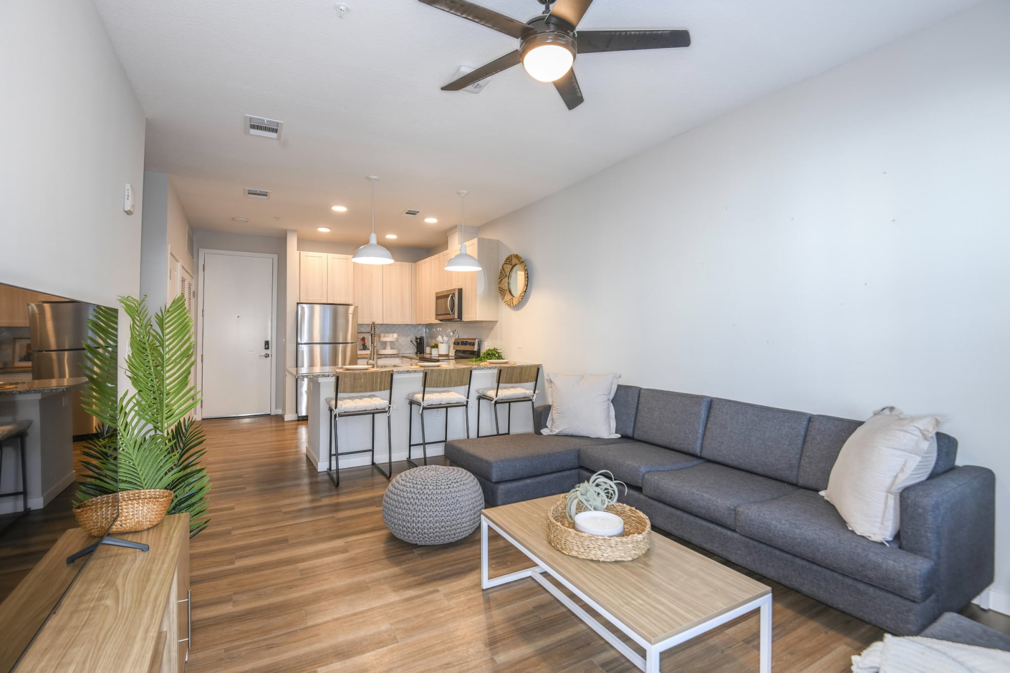 Open-concept apartment living and kitchen area with gray sectional and breakfast bar at The Griffin