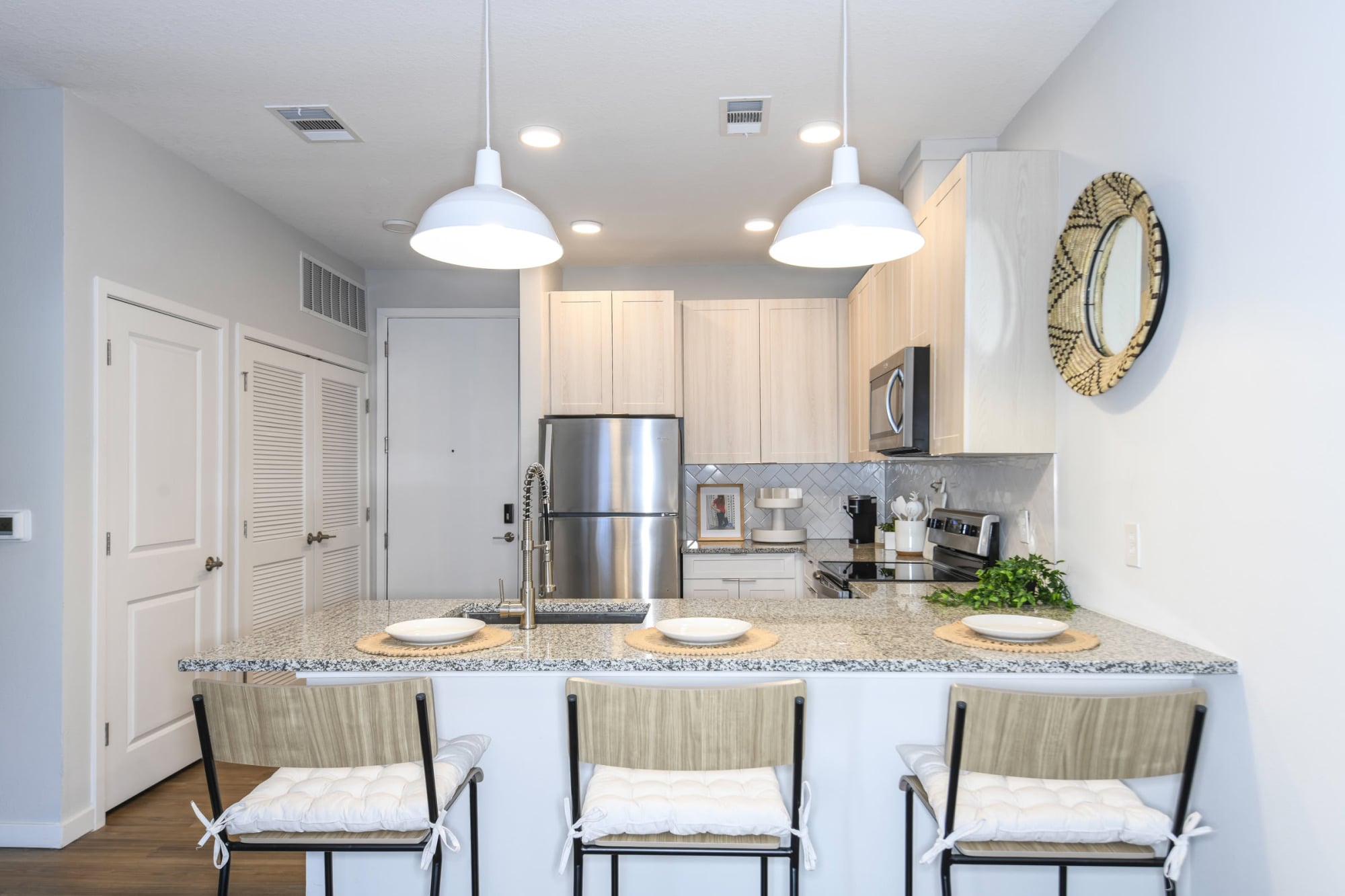 Apartment kitchen with granite breakfast bar, light wood cabinets, and pendant lighting at The Griffin