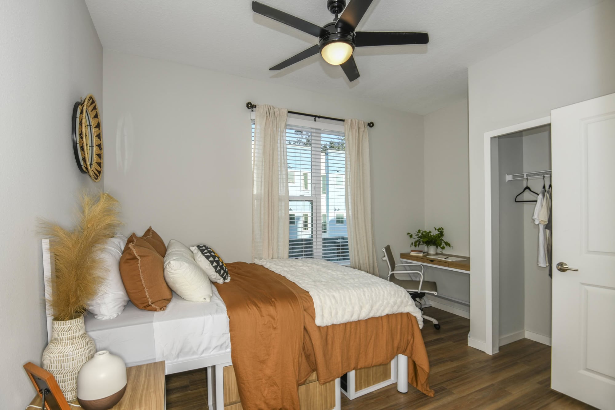 Furnished apartment bedroom with desk, walk-in closet, and large window at The Griffin