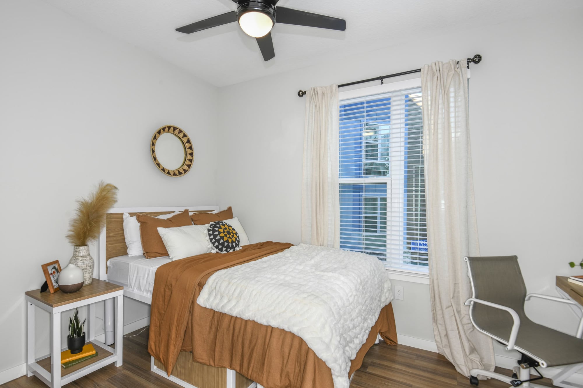 Furnished apartment bedroom with full bed, desk, and natural light at The Griffin