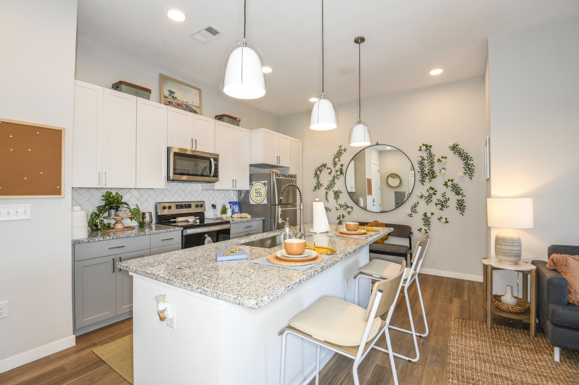 Open apartment kitchen with three-pendant island, white shaker cabinets, and stainless appliances at Stadium House