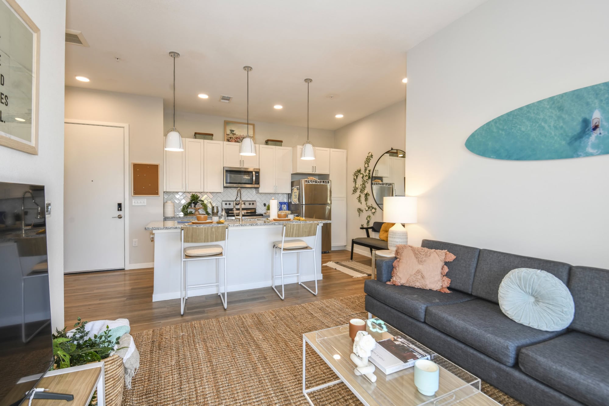 Apartment living room and kitchen with surfboard art and sectional sofa at Stadium House