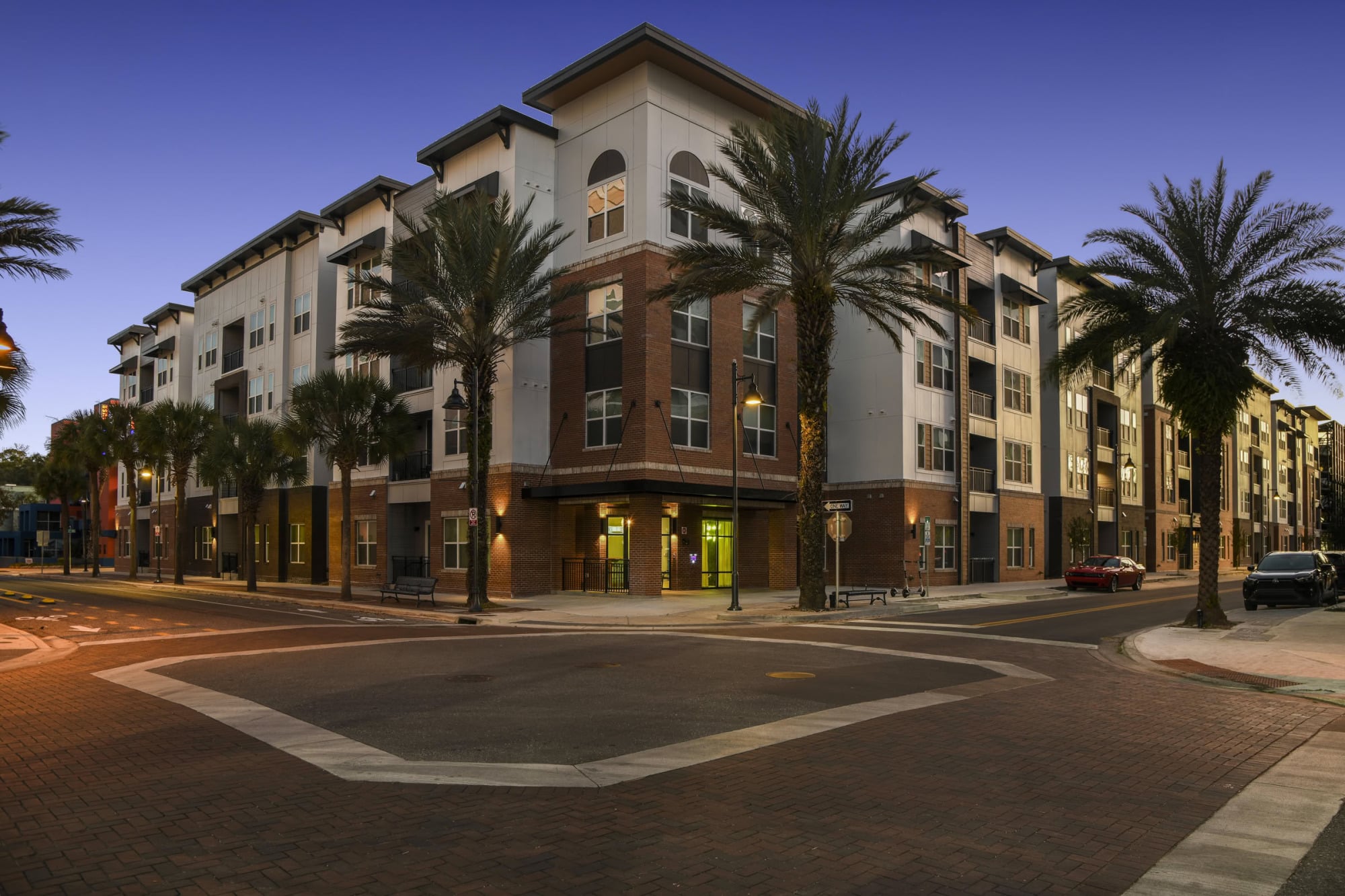 Dusk corner view of Stadium House apartments with palm trees and brick base