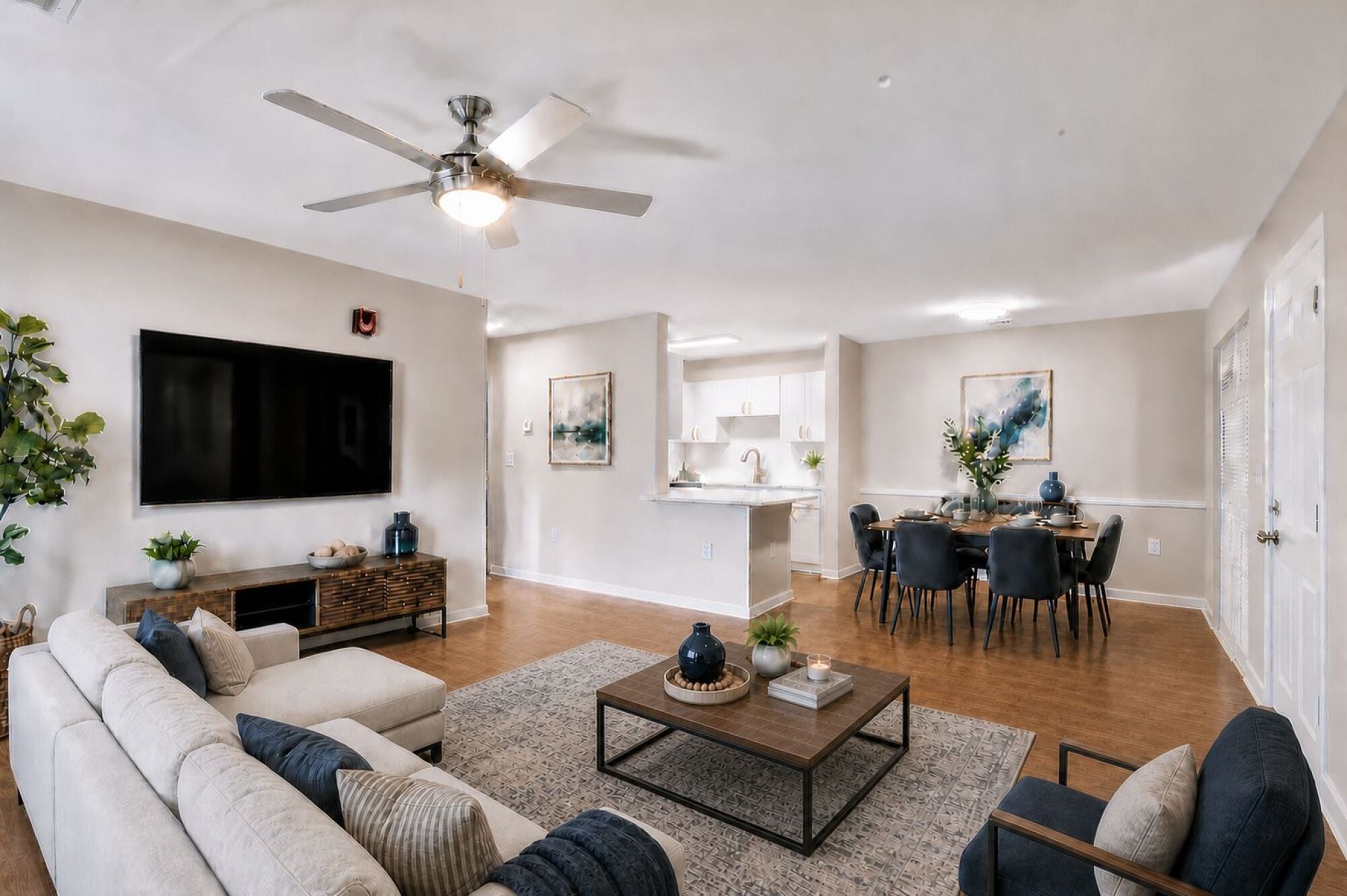 Modern open-plan living and dining area with neutral tones, large TV, and contemporary furnishings.