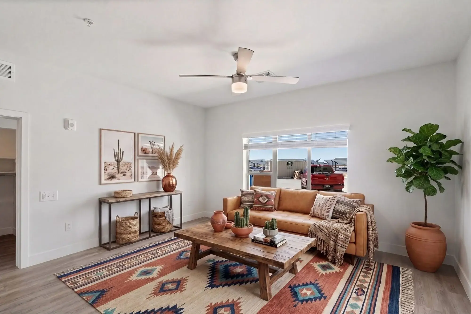 Bright living room with a tan sofa, wooden table, plants, and Southwestern decor elements.