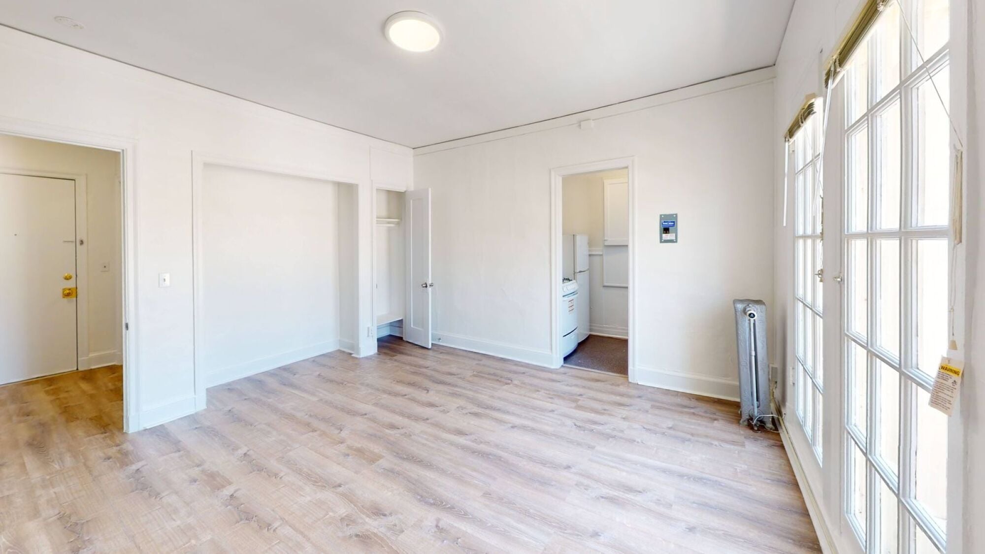 A spacious room with wooden flooring and white walls.