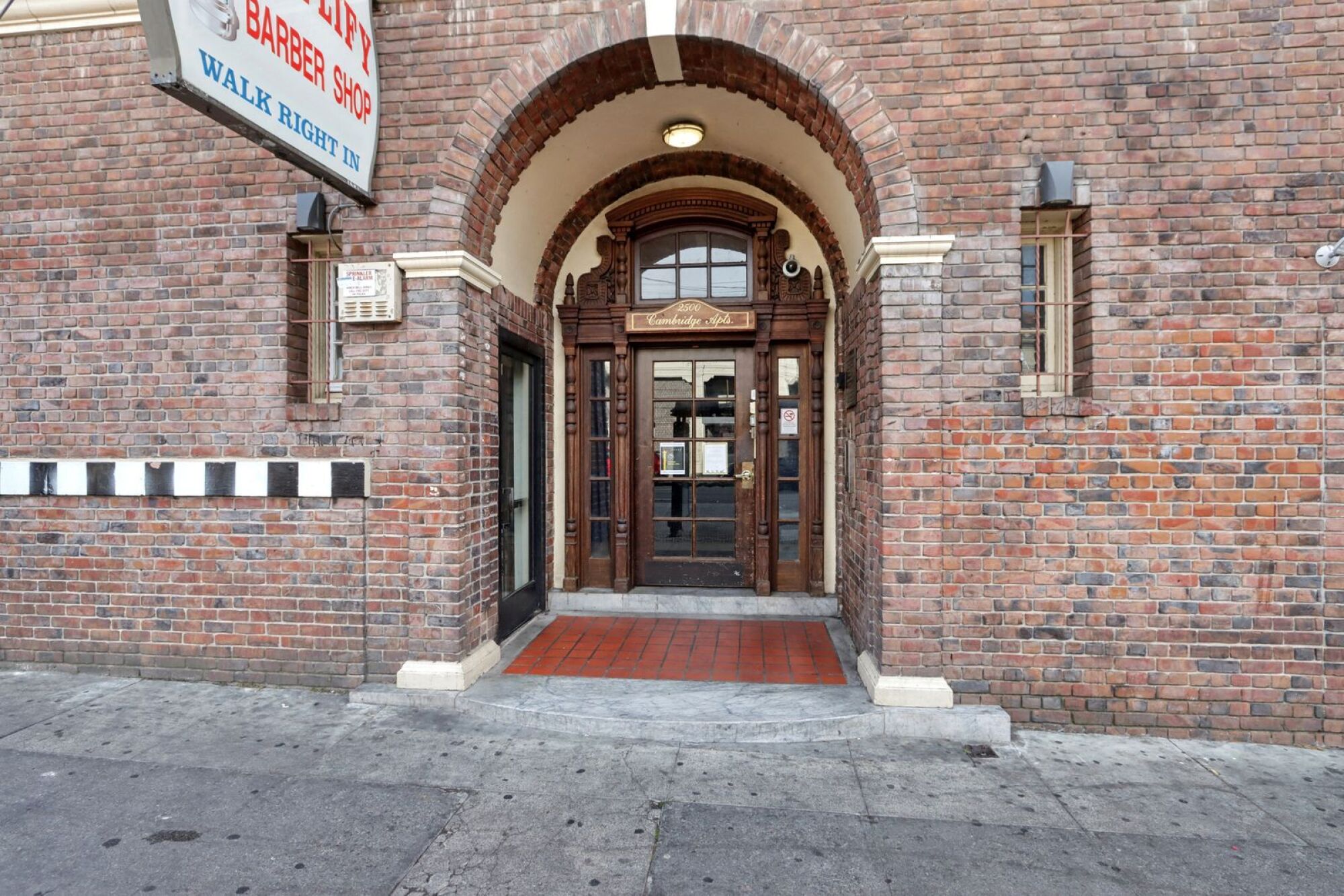 A brick building with a sign that says Barber Shop Walk Right.