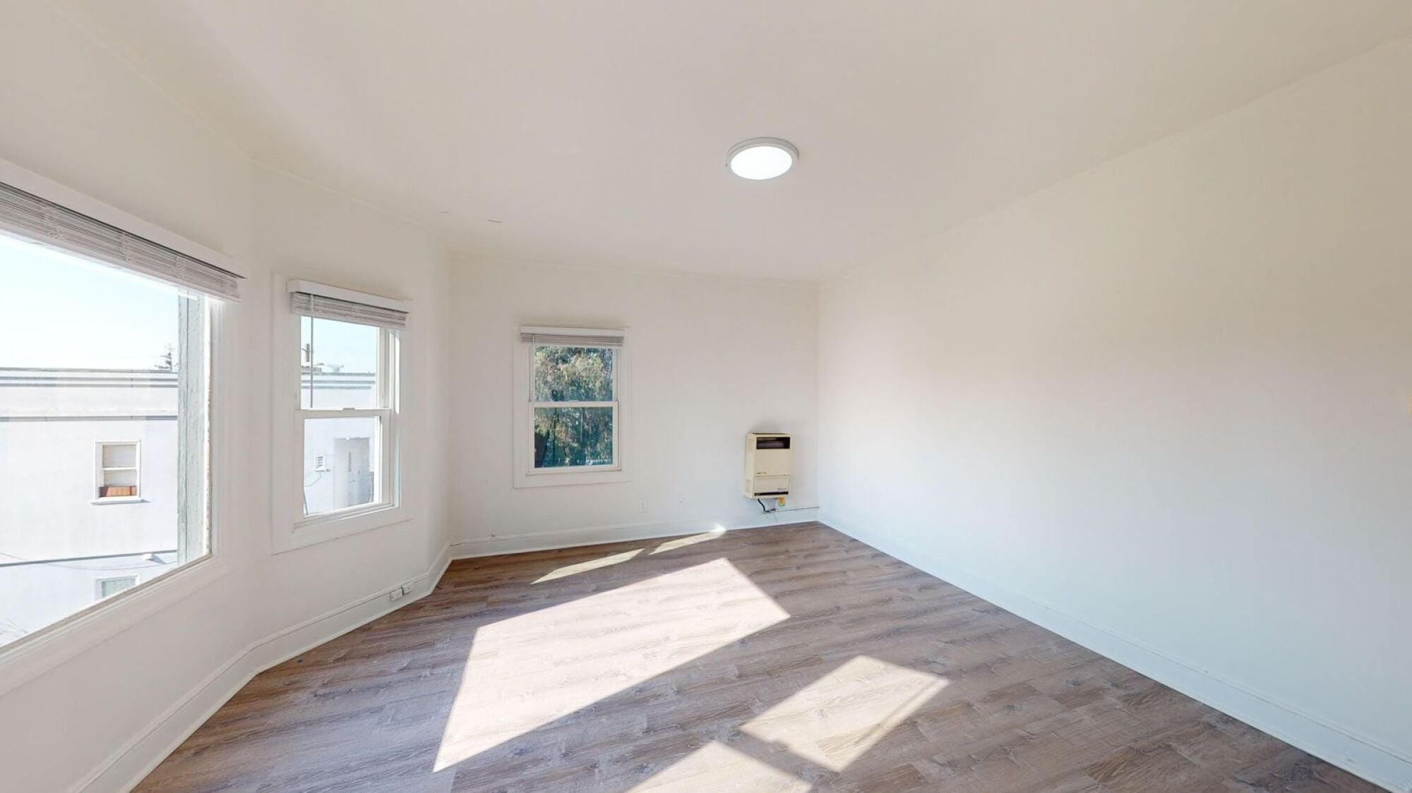 A room with a white wall and a painting hanging on it.
