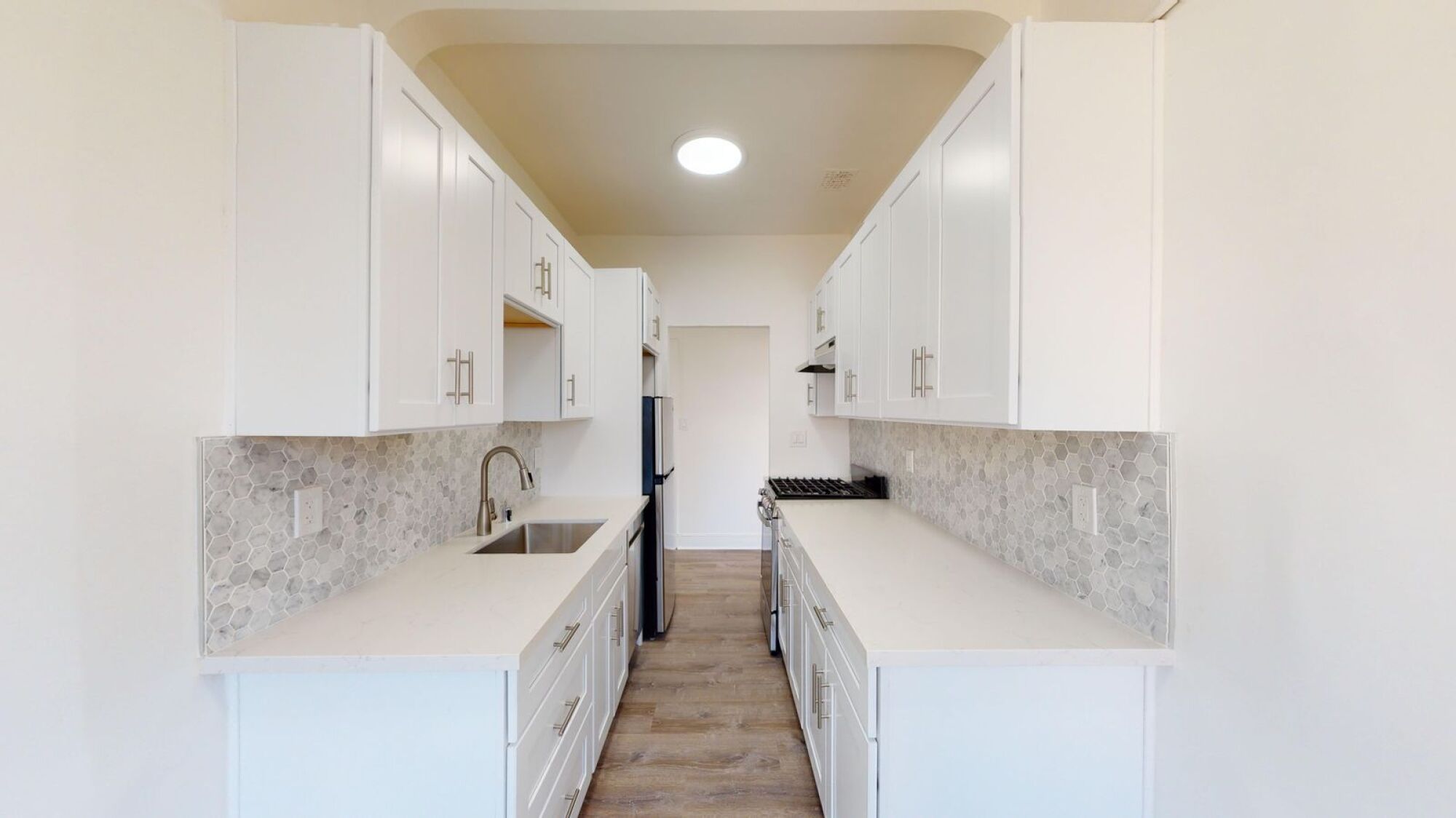 A kitchen with white cabinets and a marble backsplash.