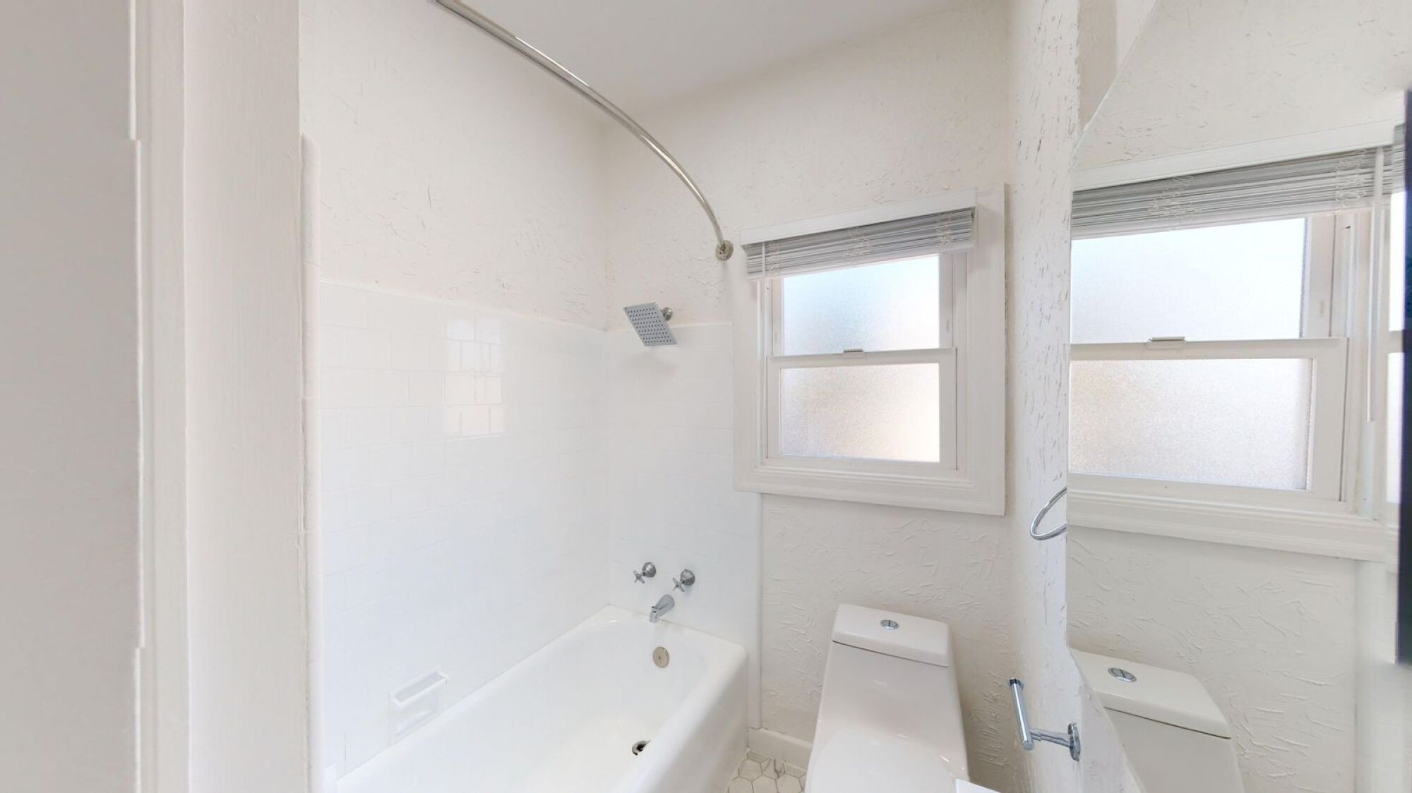 A white bathroom with a tub, toilet and sink.