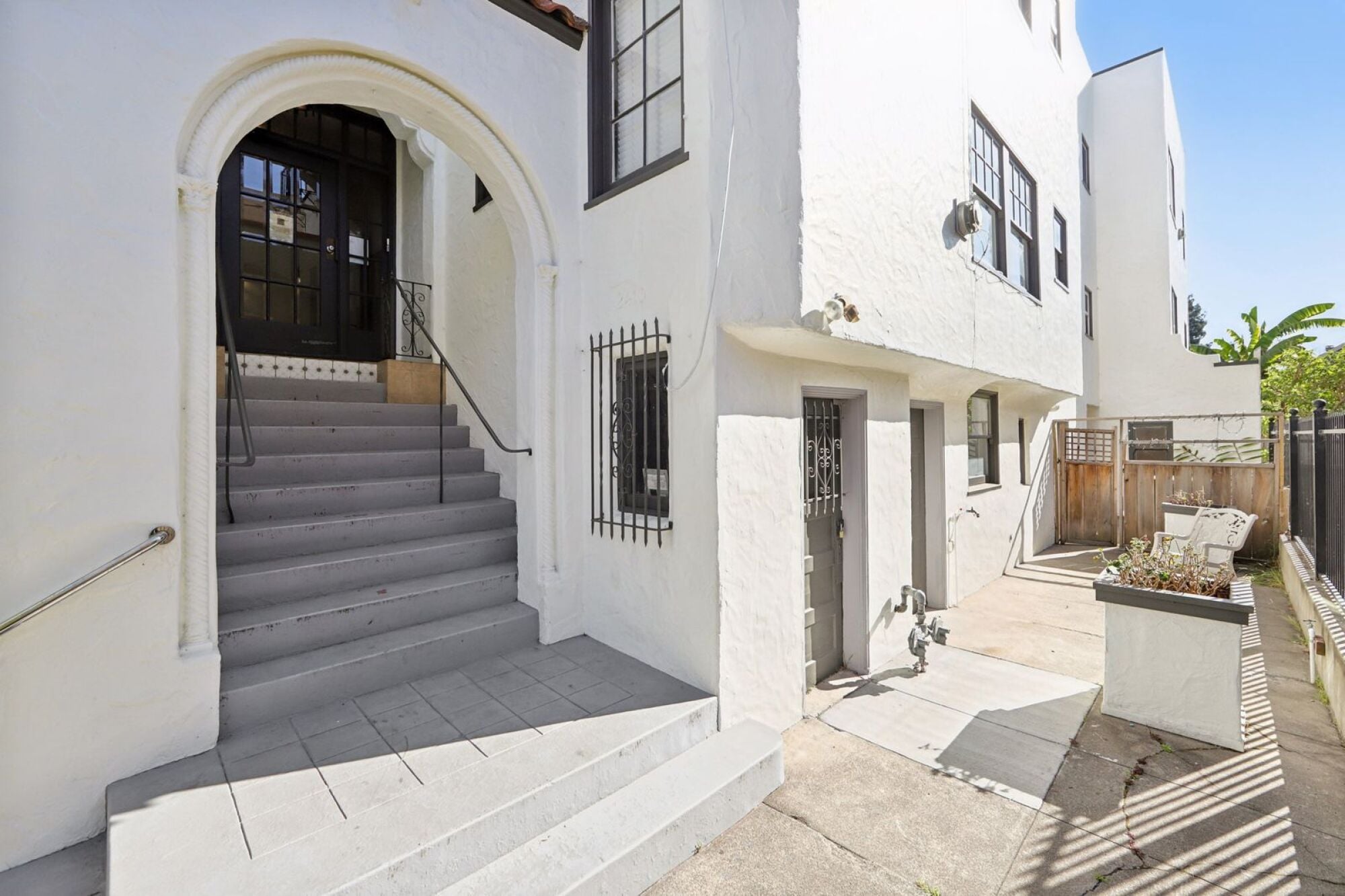 A white building with a black door and a staircase leading to it.