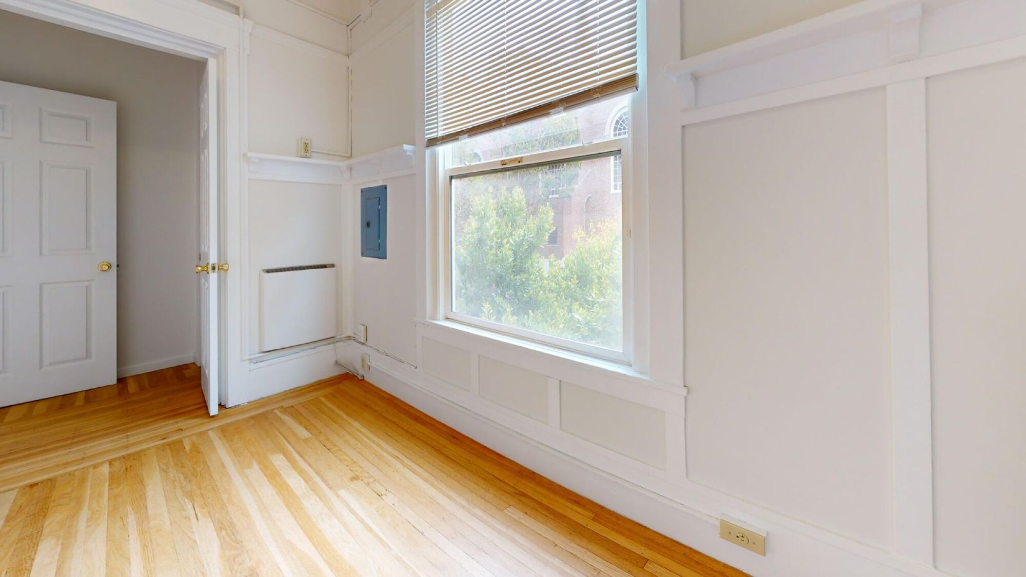 A room with a window and wooden floors.