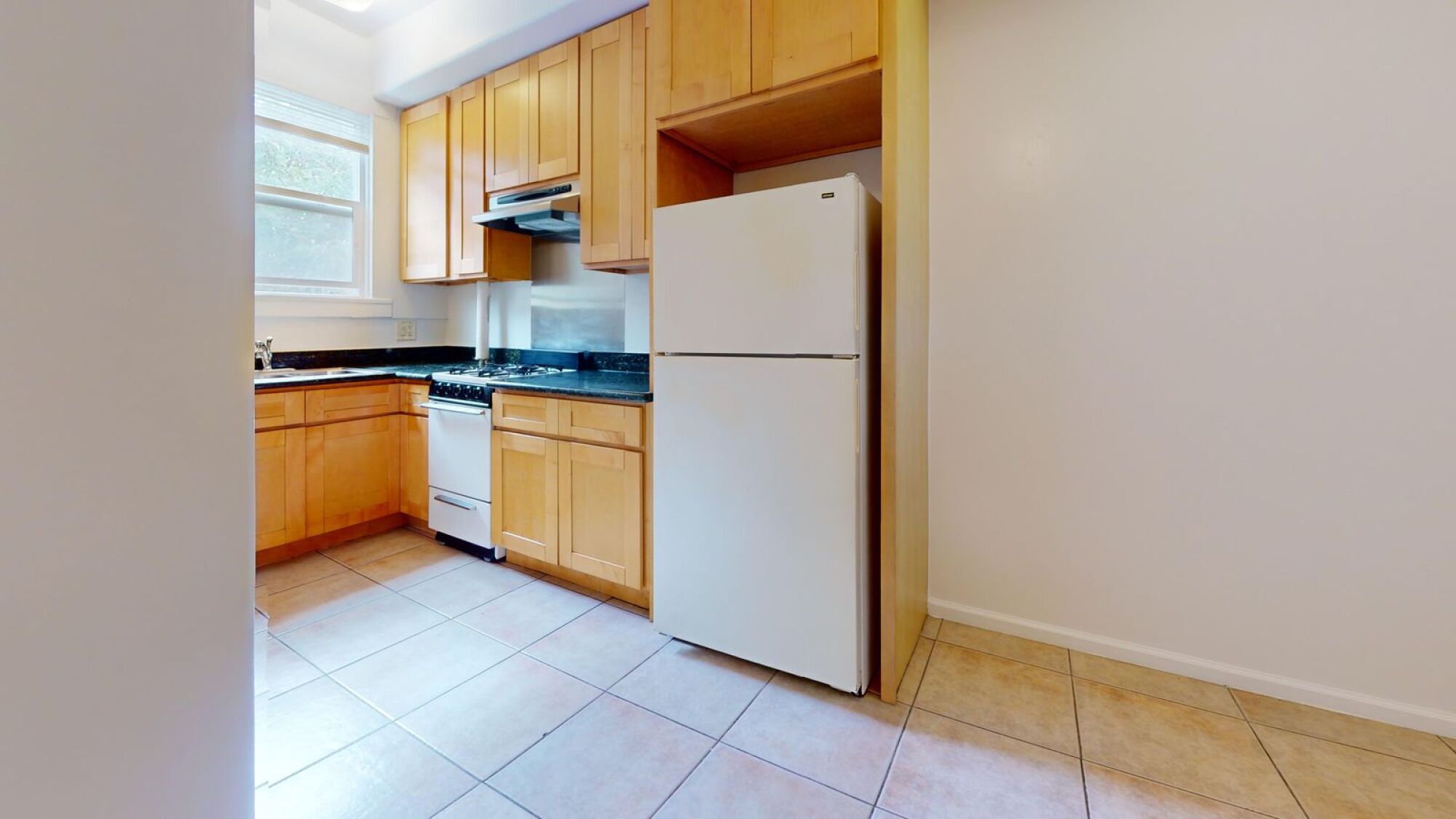 A kitchen with a white refrigerator and wooden cabinets.