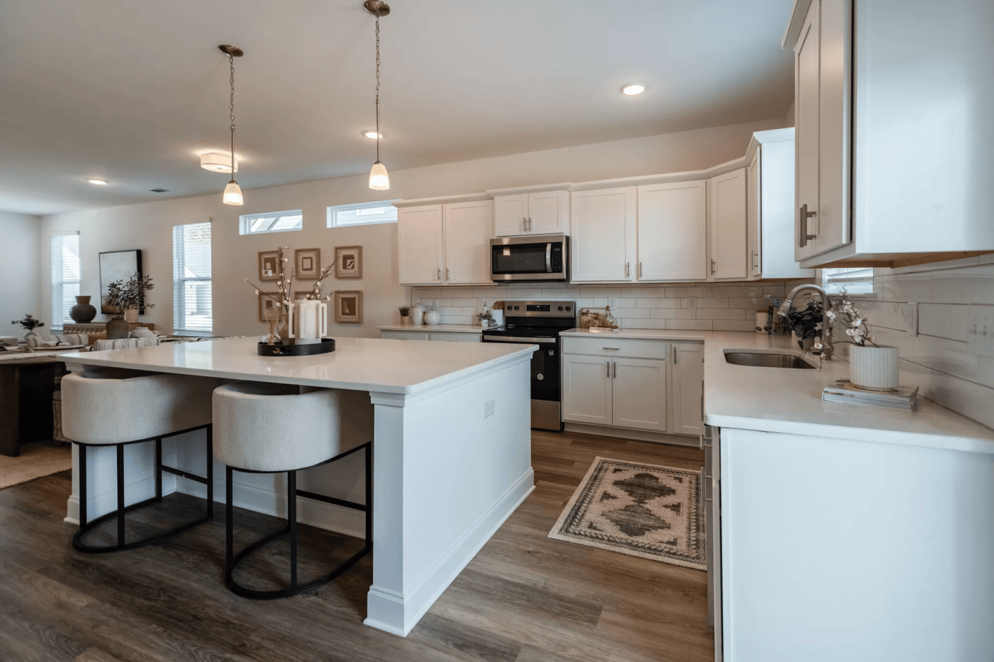 A kitchen with a white island and bar stools.