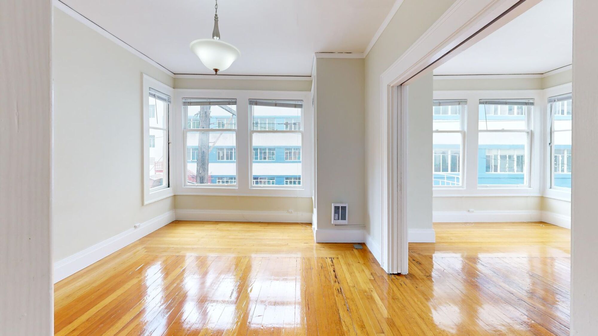 A room with wooden floors and a large window overlooking a city.
