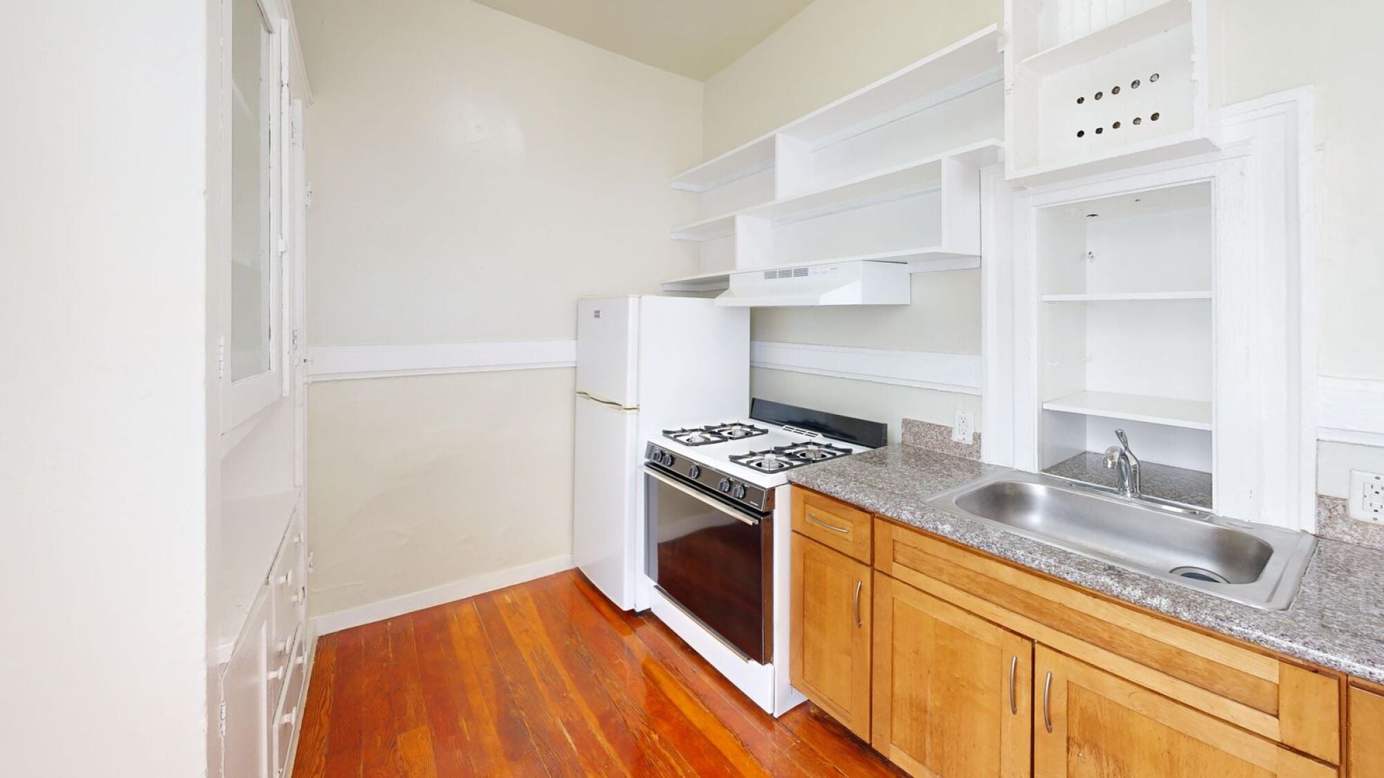 A kitchen with white appliances and wooden floors.