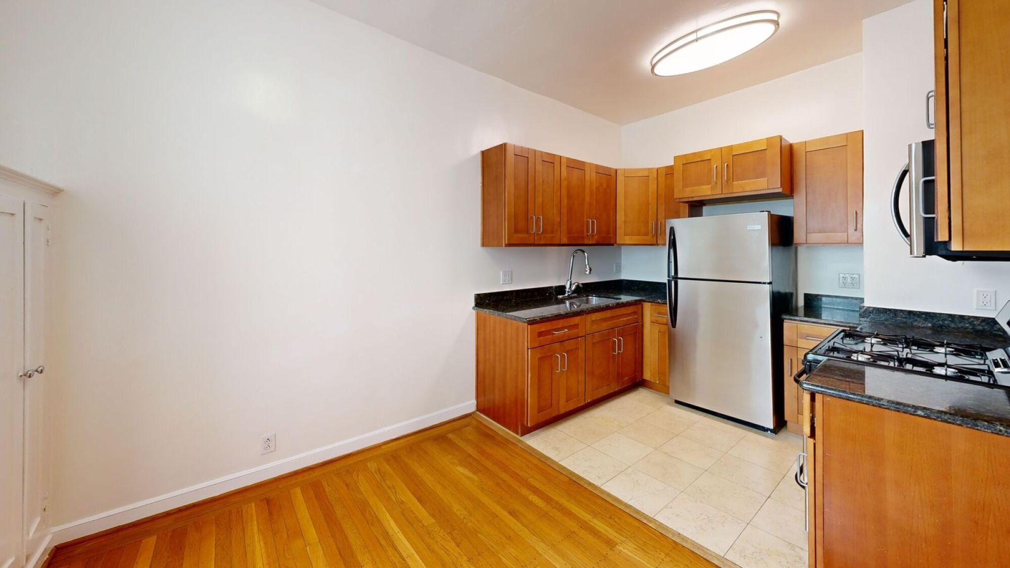 A kitchen with wooden cabinets and a stainless steel refrigerator.