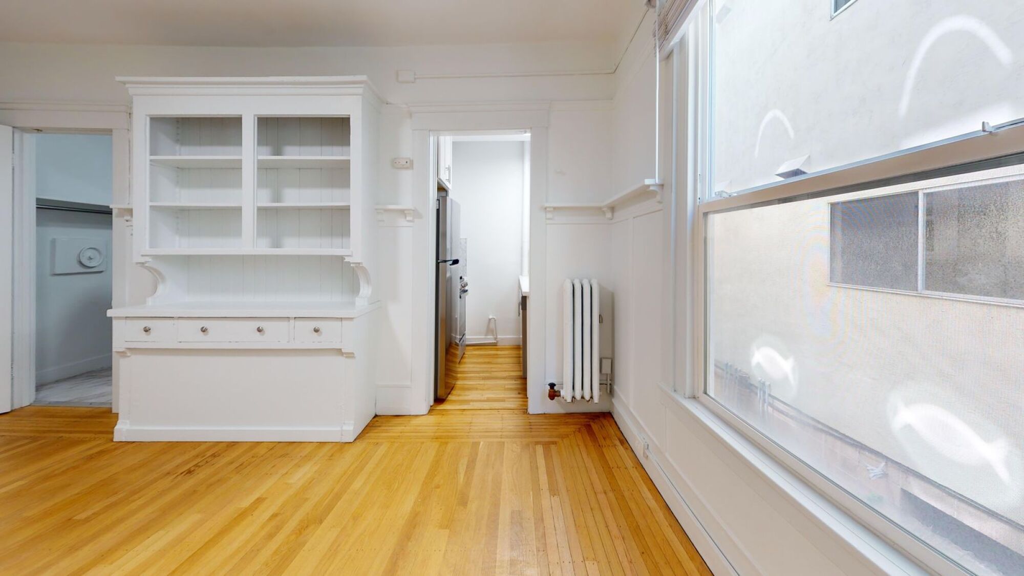 A kitchen with white cabinets and a wooden floor.