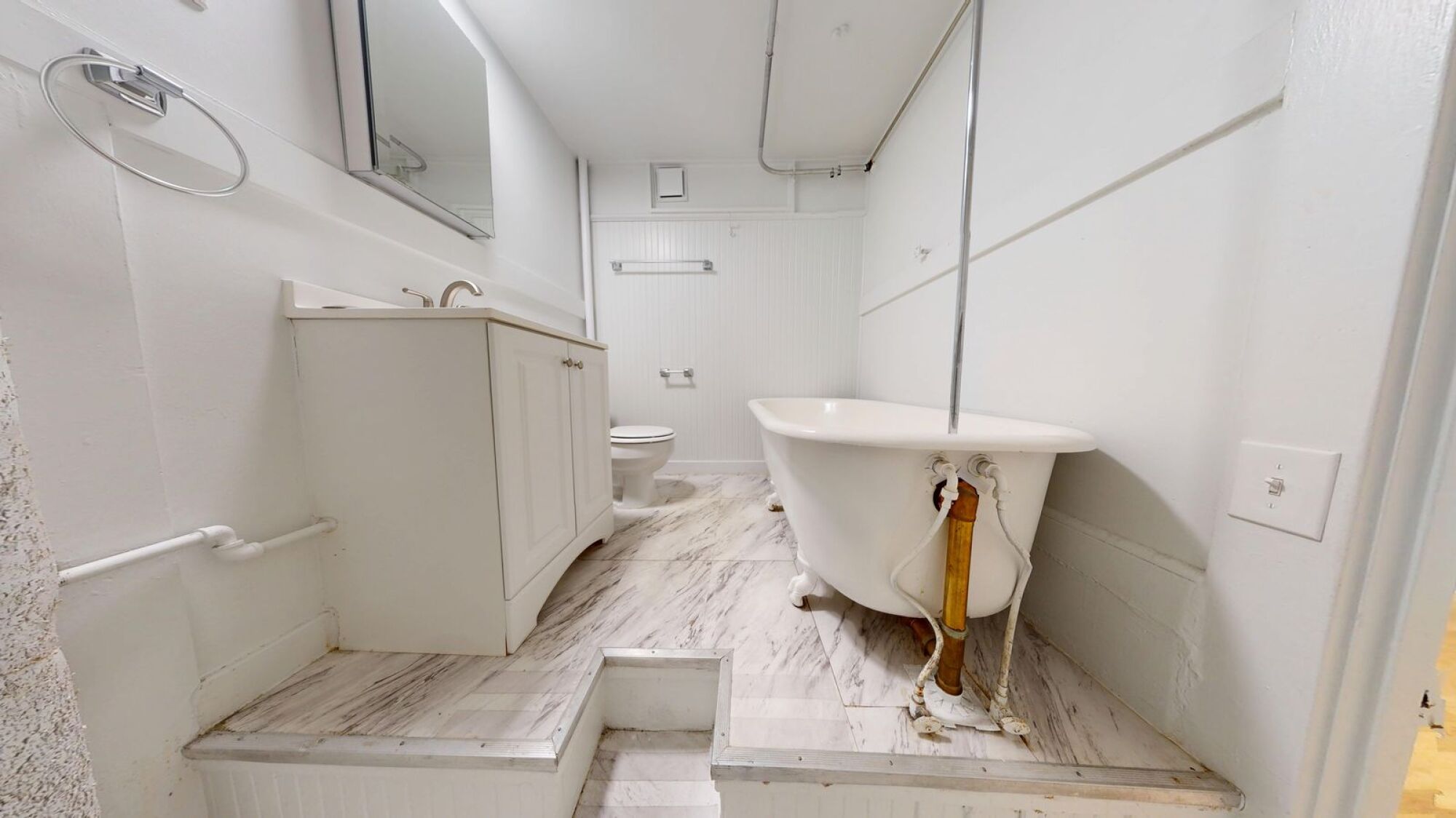 A white bathroom with a tub and toilet.